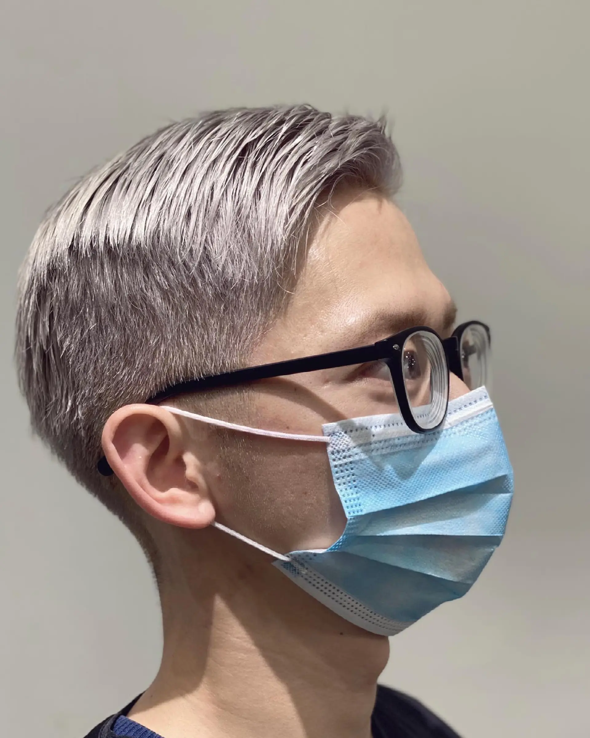 A short, textured buzz cut, bleached to a striking platinum blonde/silver. 1