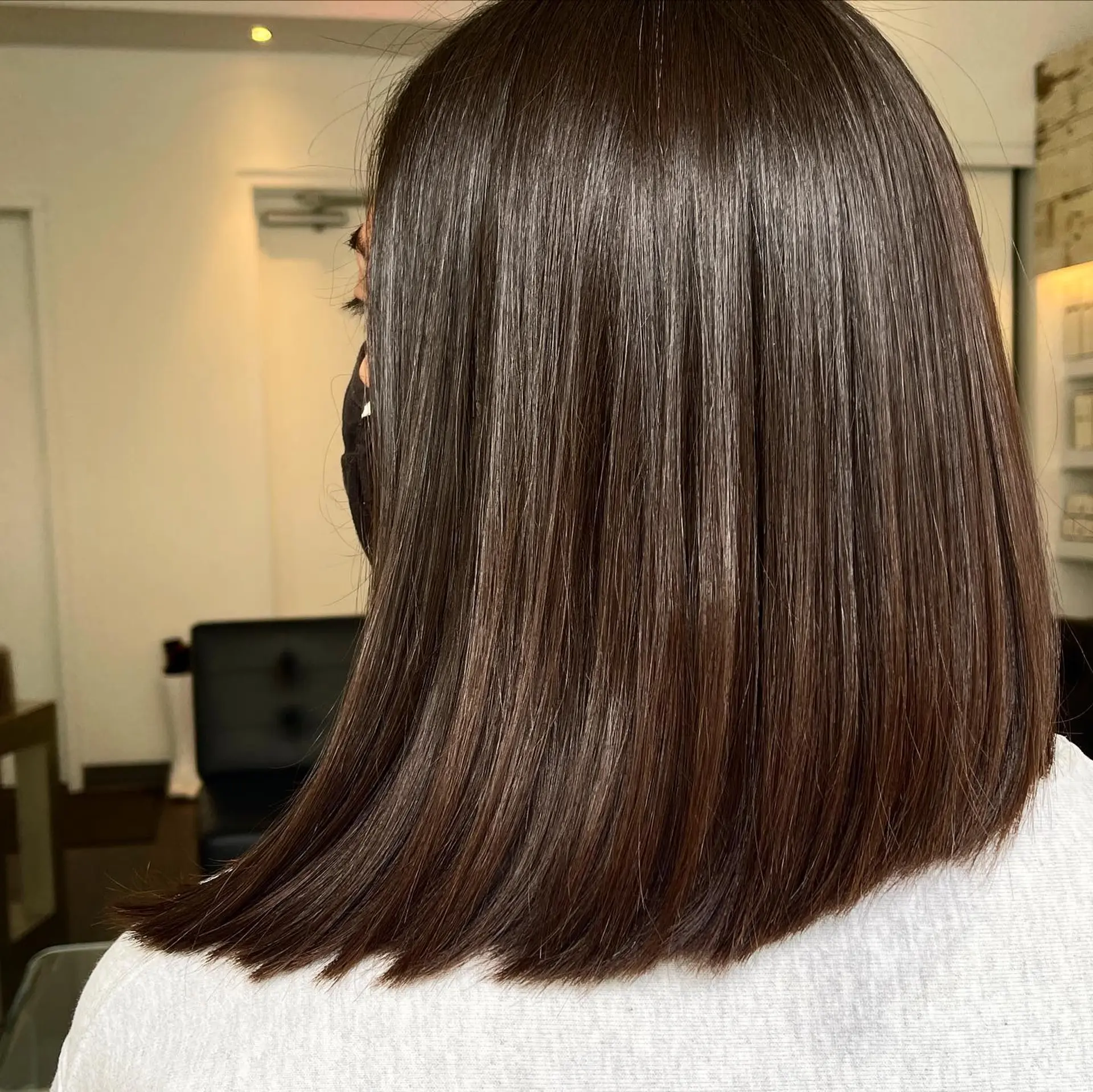 A sleek, shoulder-length blunt lob cut styled ultra-straight with a glossy finish. 1