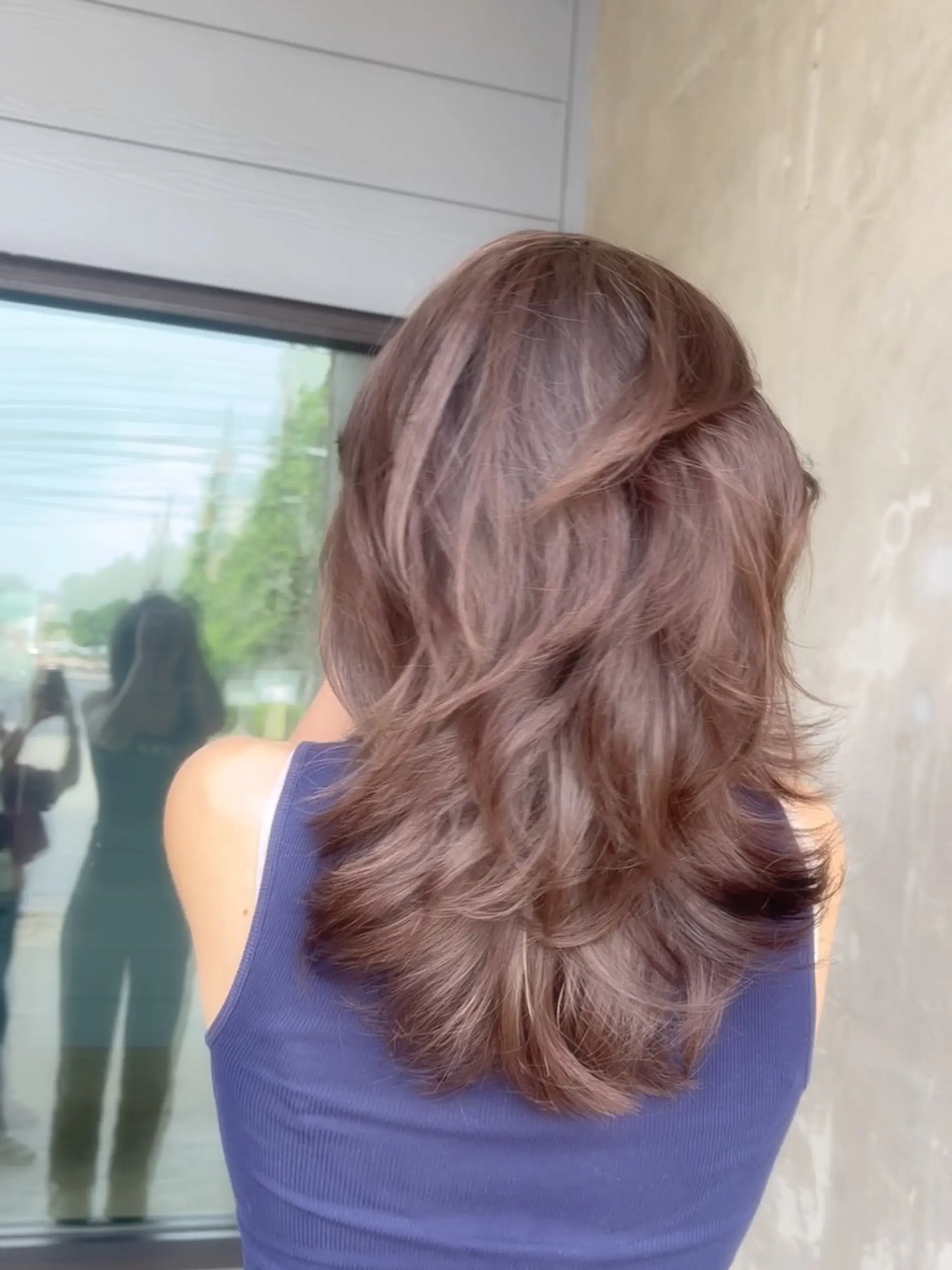 Medium-length ash brown layered haircut styled with airy movement and flipped, textured ends. 1