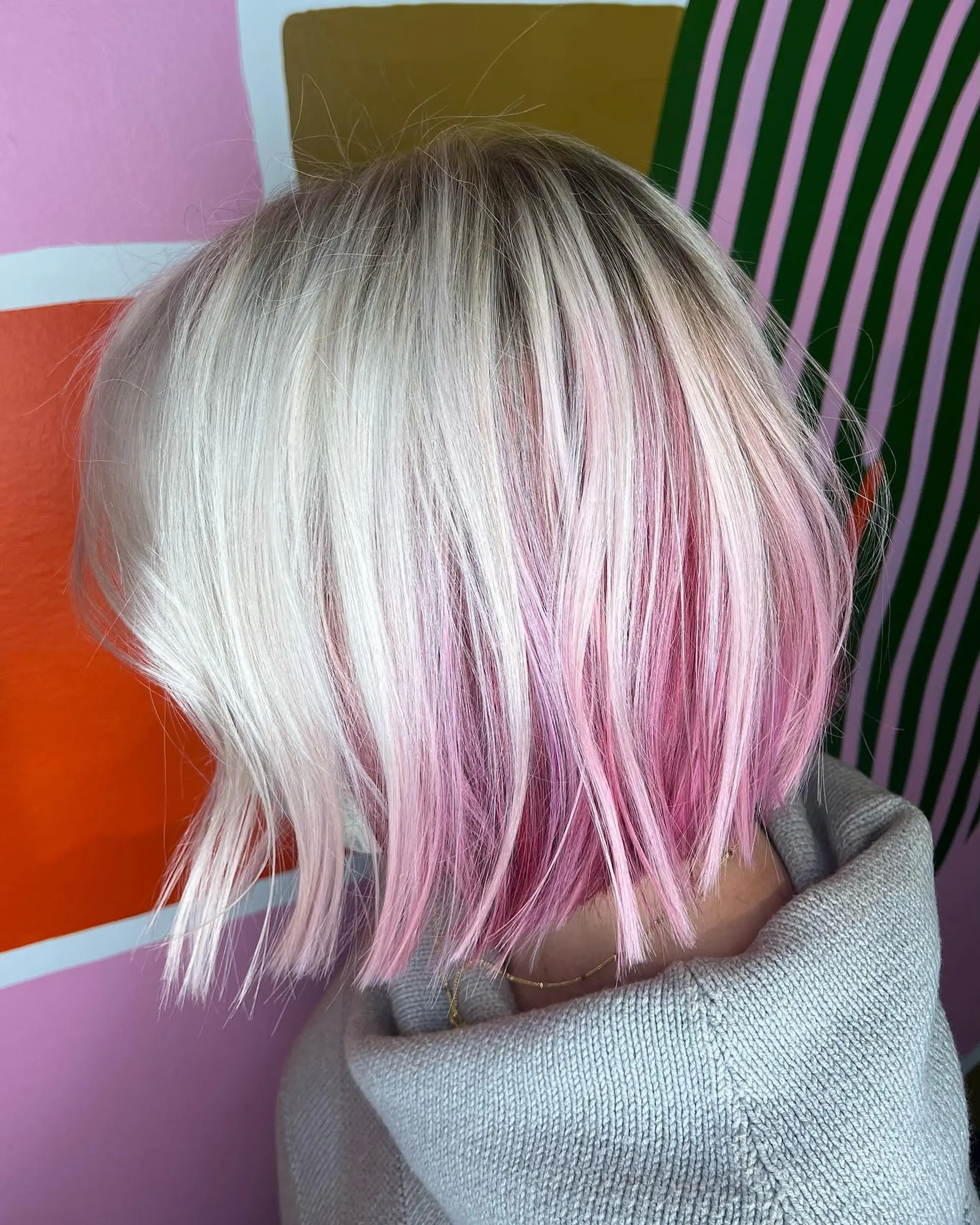 A sleek, textured blunt bob cut featuring icy platinum blonde hair accented with vibrant pastel pink peekaboo undertones. 1