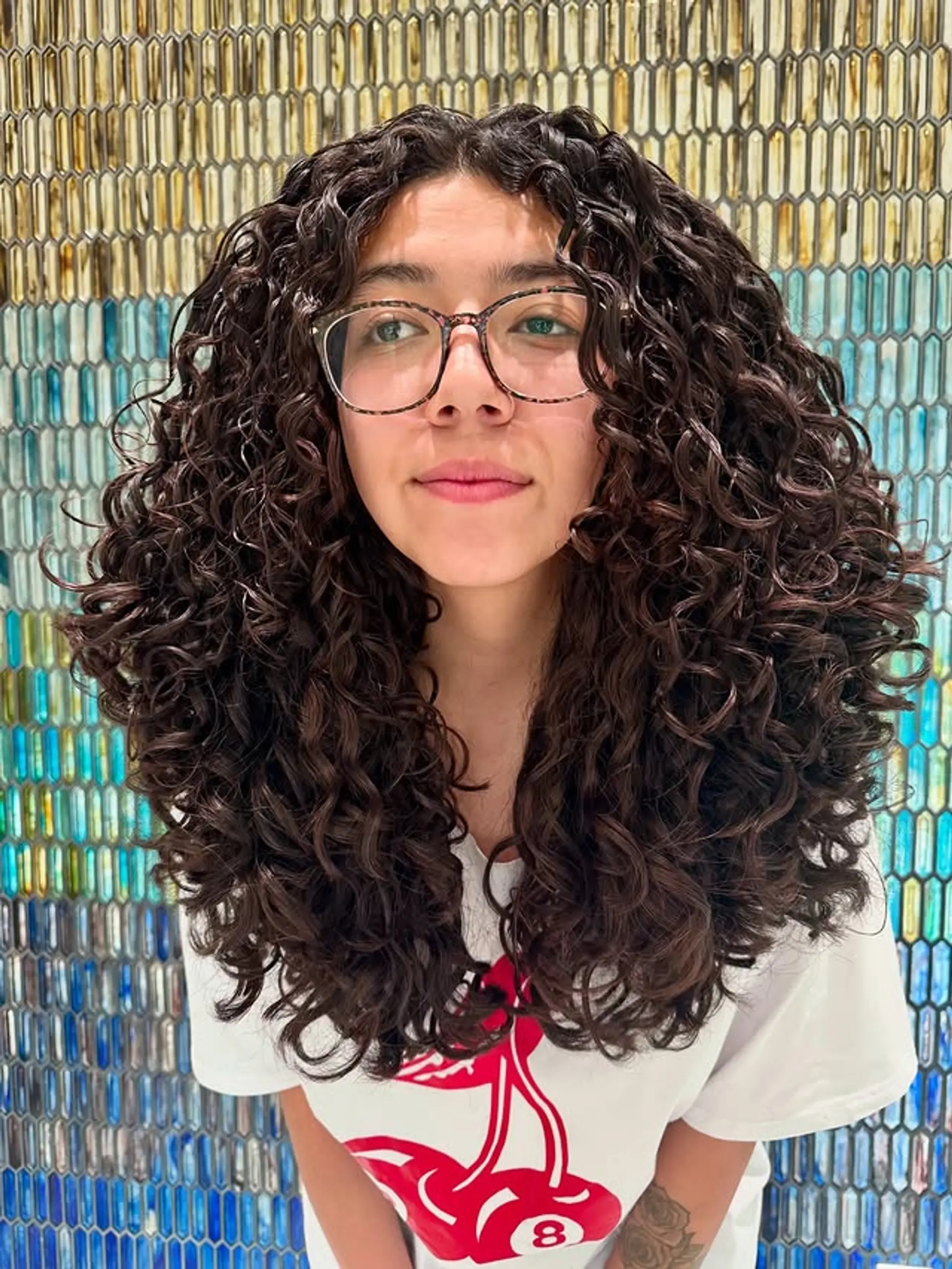 Long layered curly cut designed to enhance natural curl definition and create volume. 1