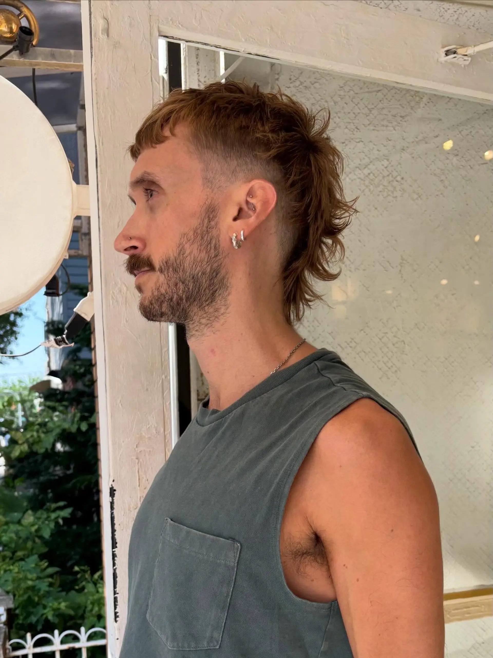 A modern textured mullet featuring a clean temple skin fade and short, textured fringe with longer wavy layers at the nape. 1