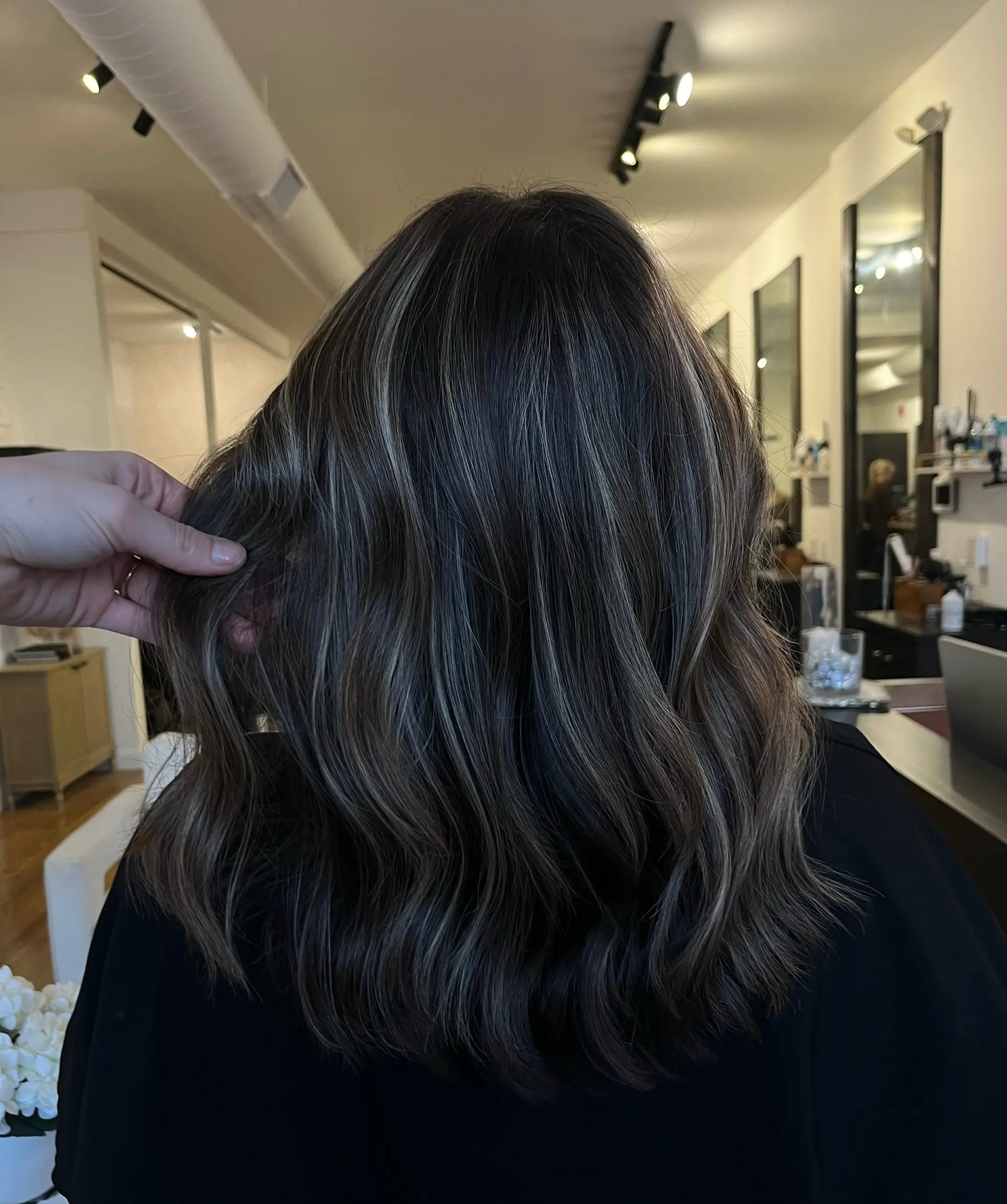 Medium-length dark brunette hair featuring fine, natural beige foilyage highlights styled in soft, loose waves. 1