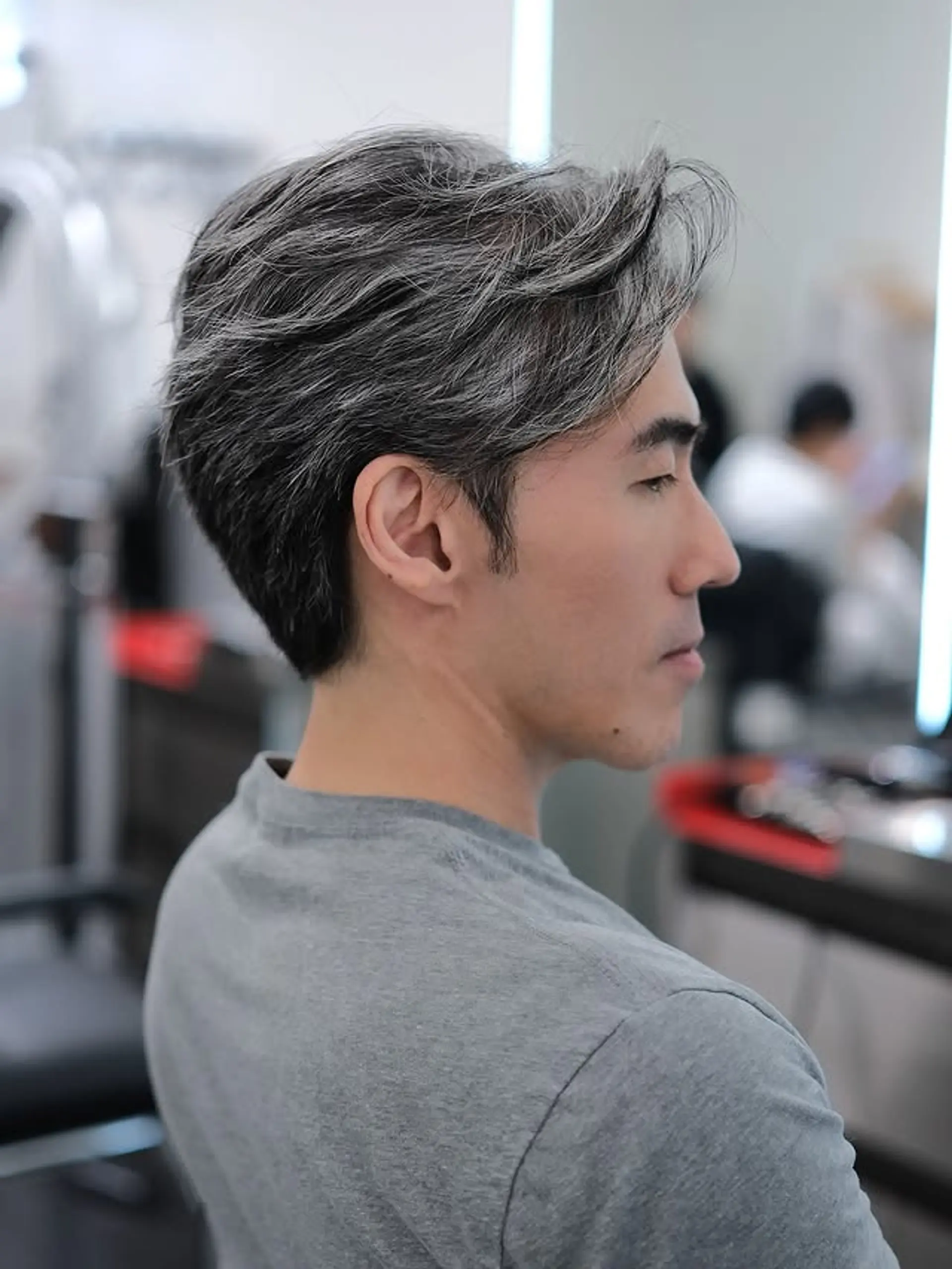 A modern men's hairstyle with short, tapered sides and a longer, wavy top that is swept back to create dynamic volume and texture. 1