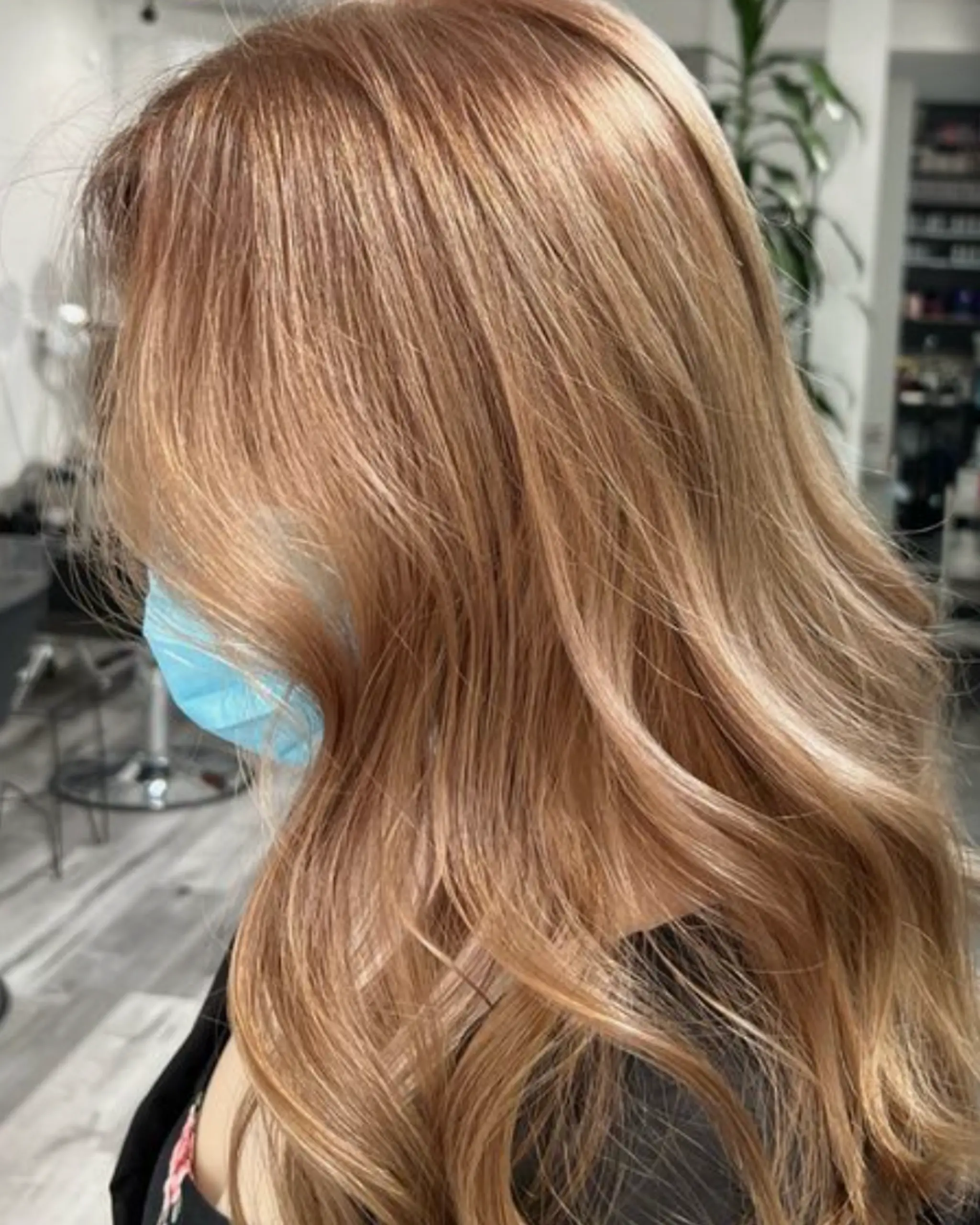 Long, wavy hairstyle with a blend of golden blonde and copper tones, featuring loose, flowing waves and soft face-framing layers.