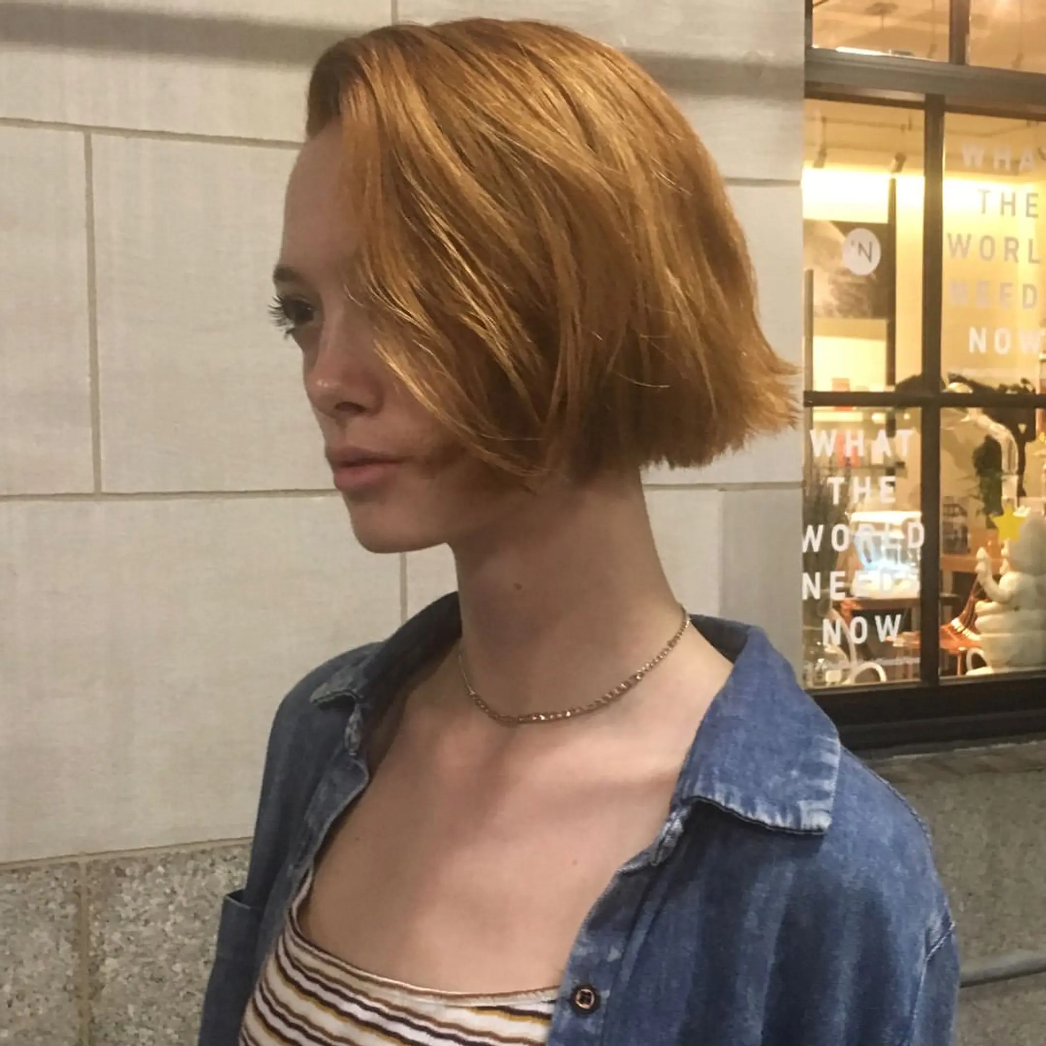 An edgy slope bob haircut with straight, short, red auburn hair. This asymmetrical bob features a side-part, giving it a modern and chic appearance. 2