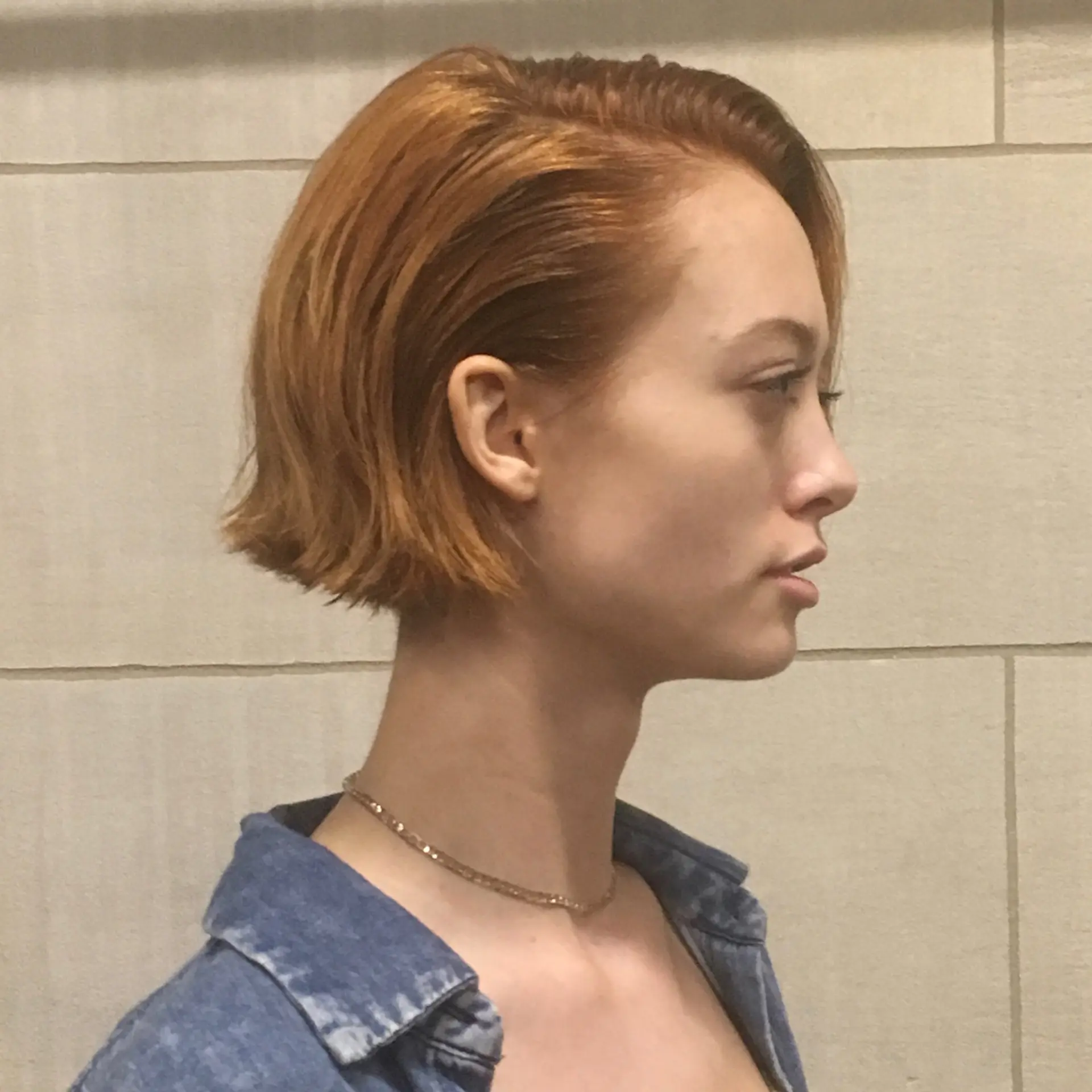 An edgy slope bob haircut with straight, short, red auburn hair. This asymmetrical bob features a side-part, giving it a modern and chic appearance. 3