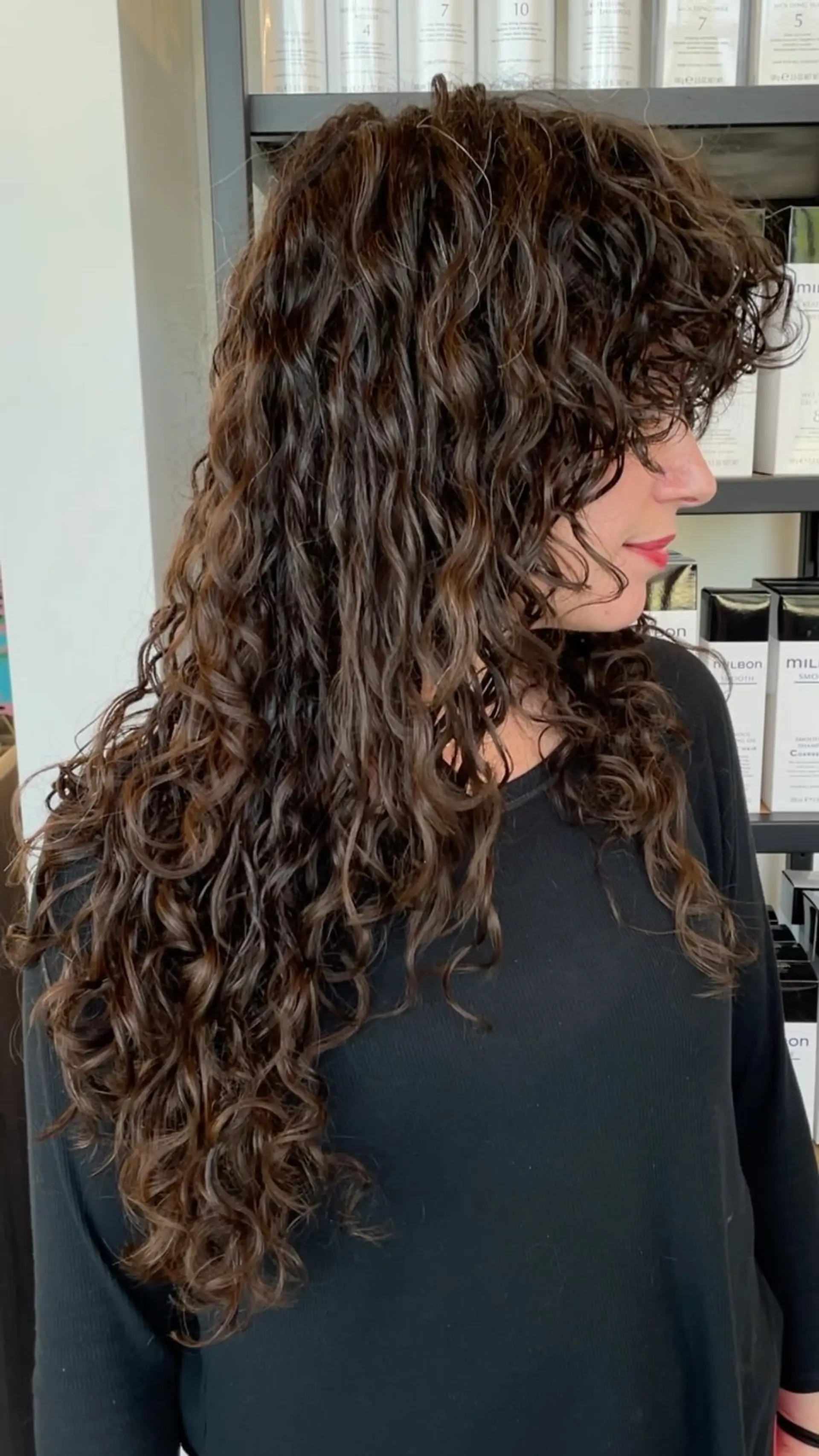Long, defined dark brown curls styled into a layered shag cut with curly bangs. 1