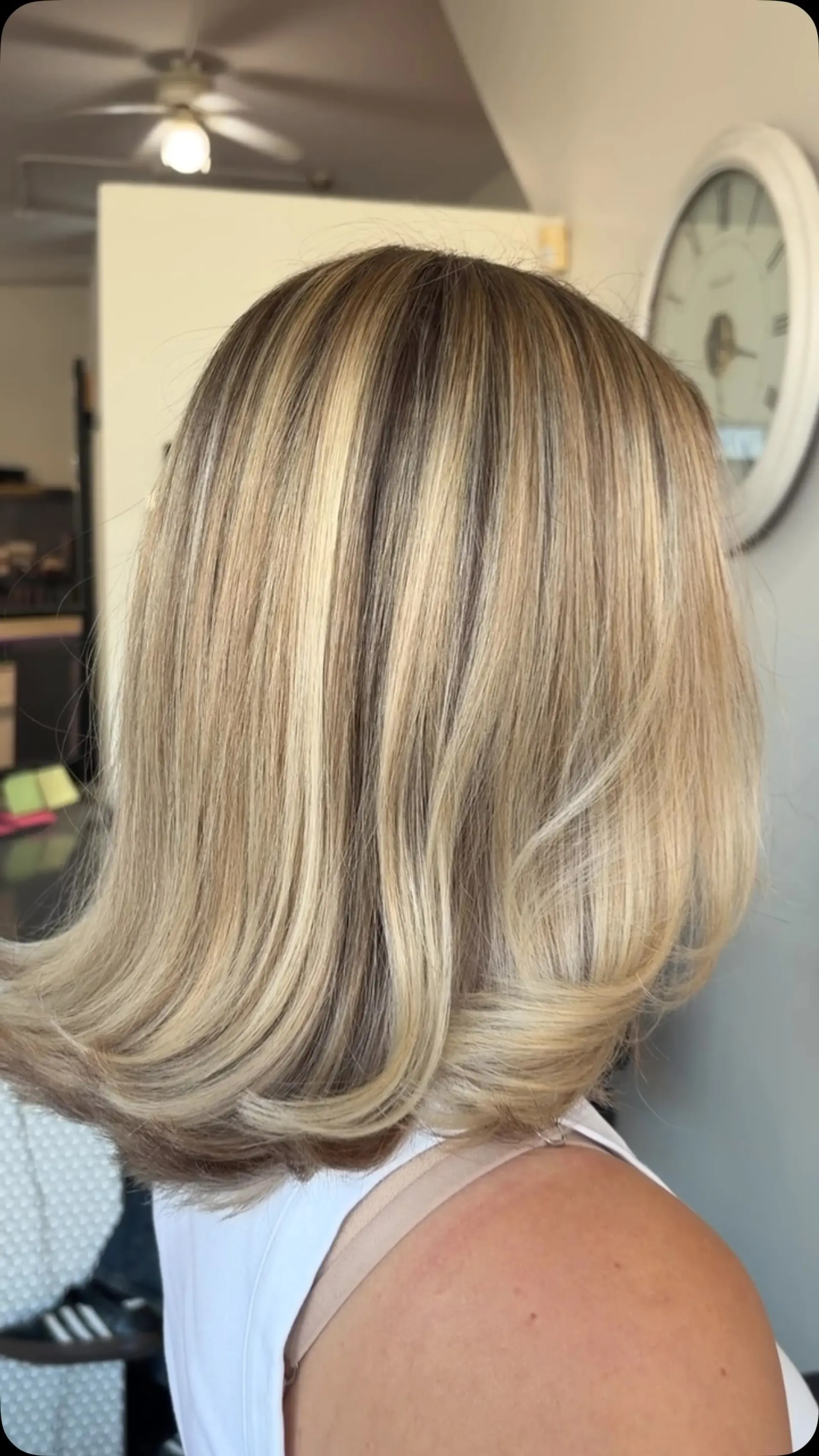 A dimensional blonde shoulder-length lob styled smooth with outward flipped ends. 1