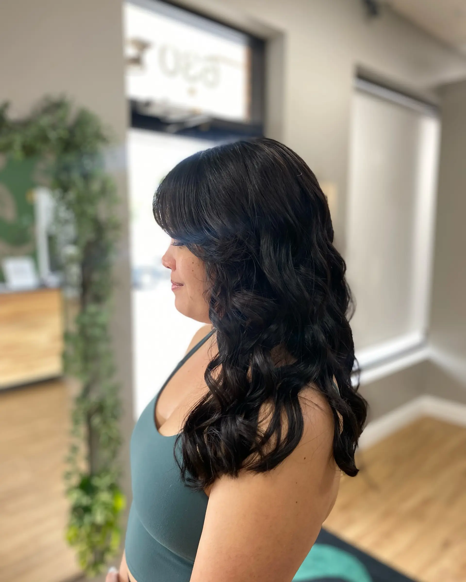 Long, glossy black hair styled into soft bouncy curls with face-framing side bangs. 1