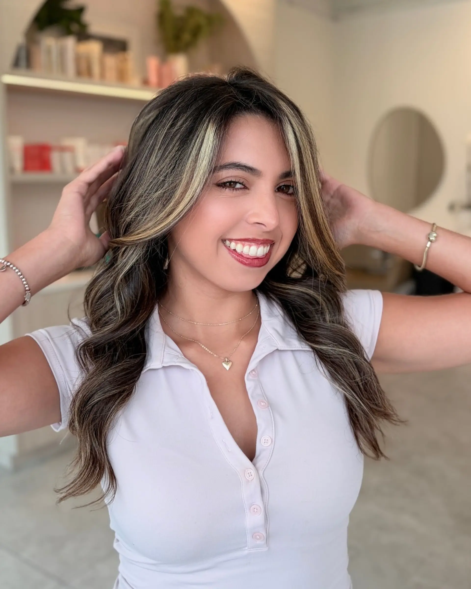 Long dark brown hair styled in soft waves with prominent blonde face-framing money piece highlights and subtle dimensional balayage. 1