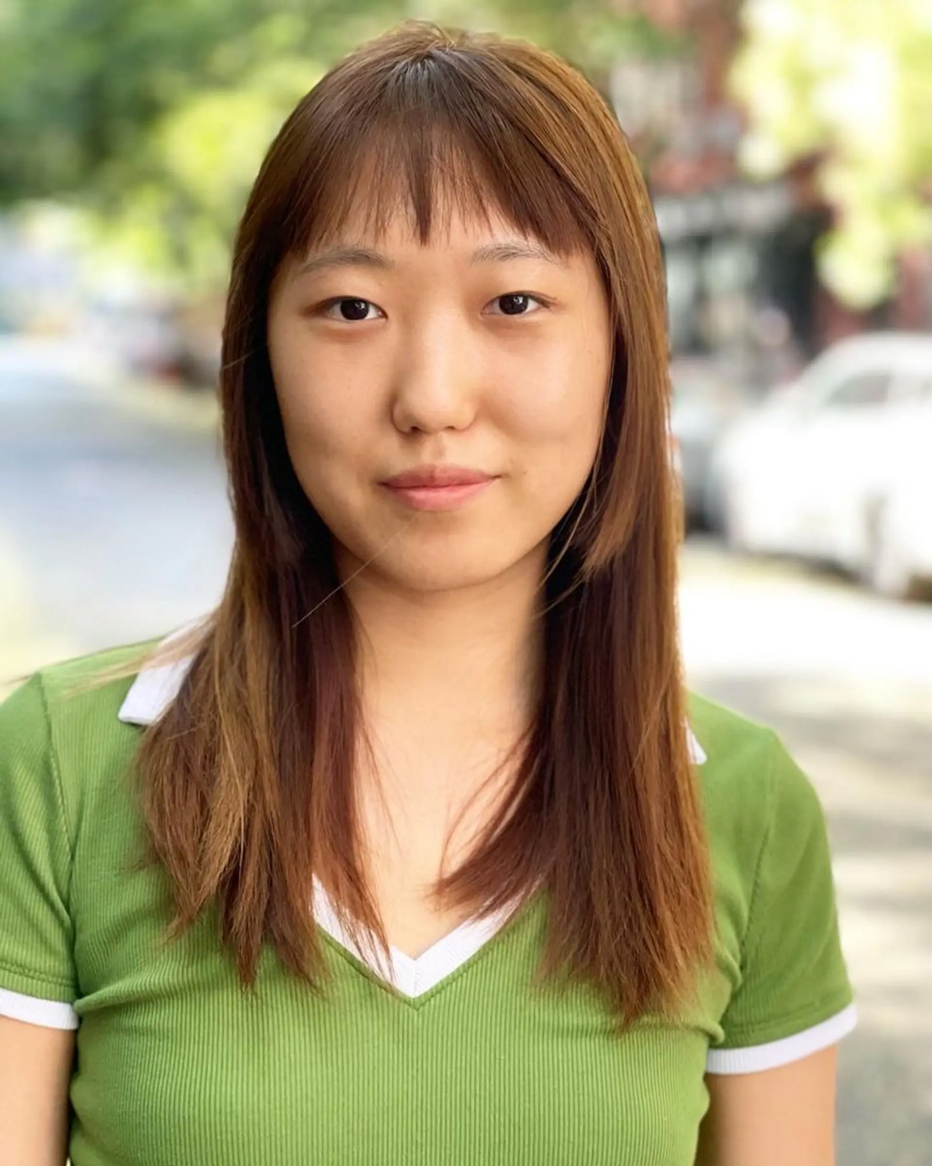 This hairstyle features layered hair with stylish curtain bangs, expertly framing the face. 1