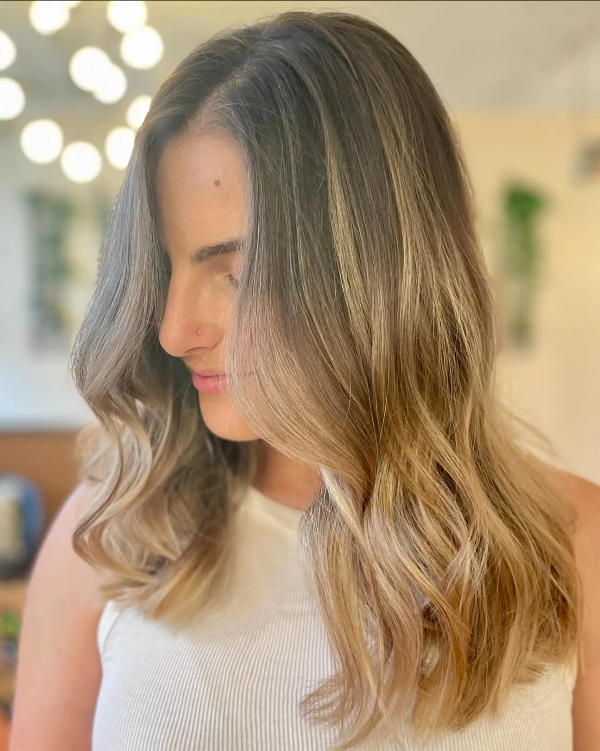 Natural, dimensional babylights blended over a light brown base and styled into soft, flowing waves with face-framing layers. 1