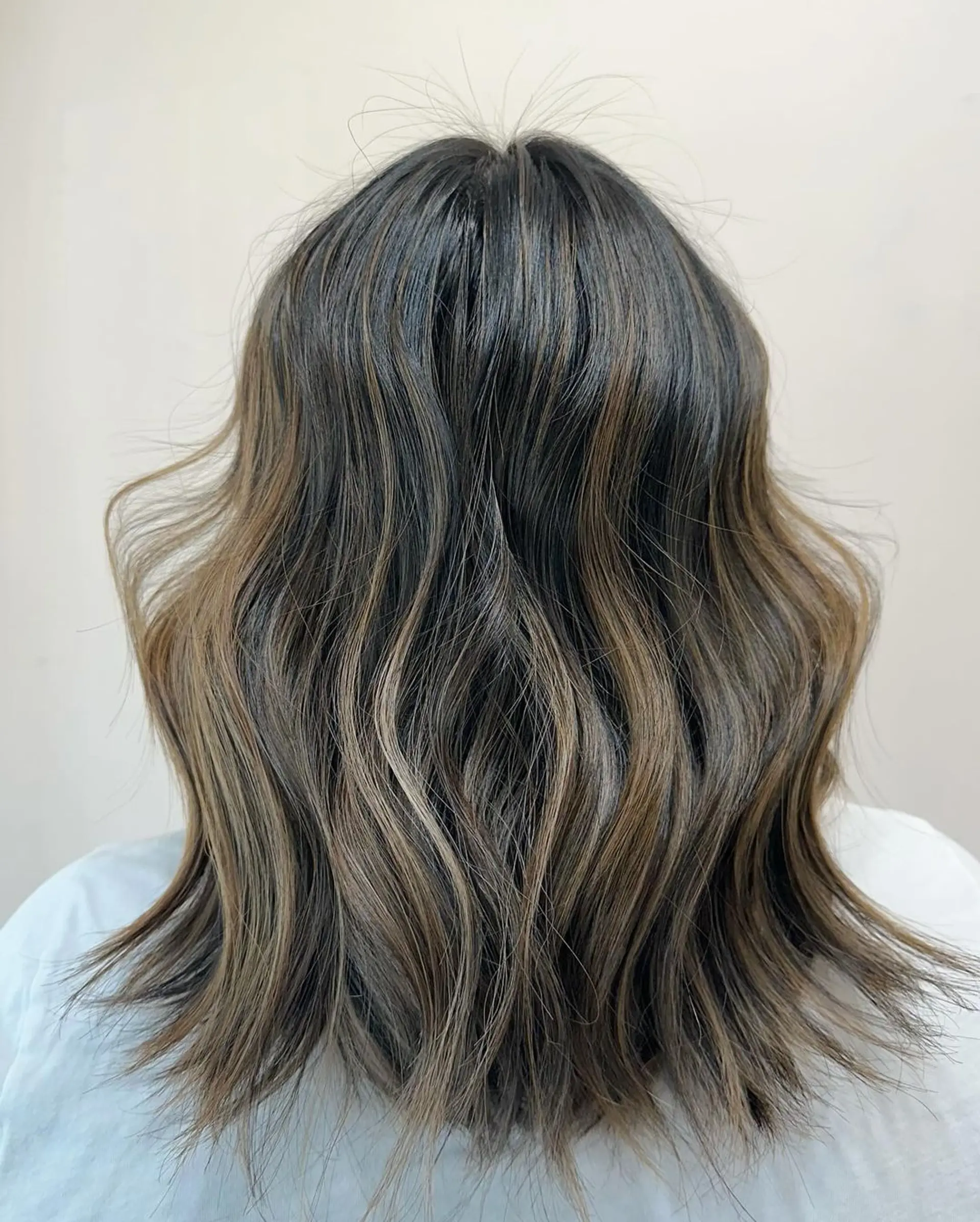 A medium-length, wavy hairstyle with brown color and blonde highlights, featuring soft waves and slight layering for a natural, beachy look. 1