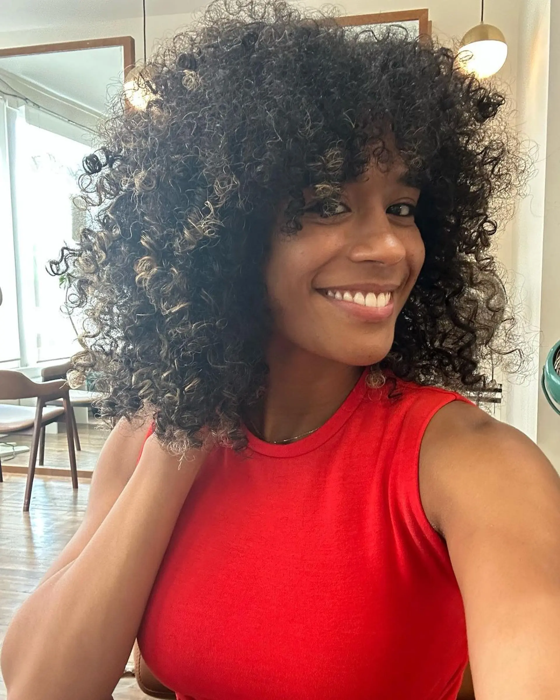 Voluminous, medium-length curly hair with black and blonde highlights with dynamic bounce. 1