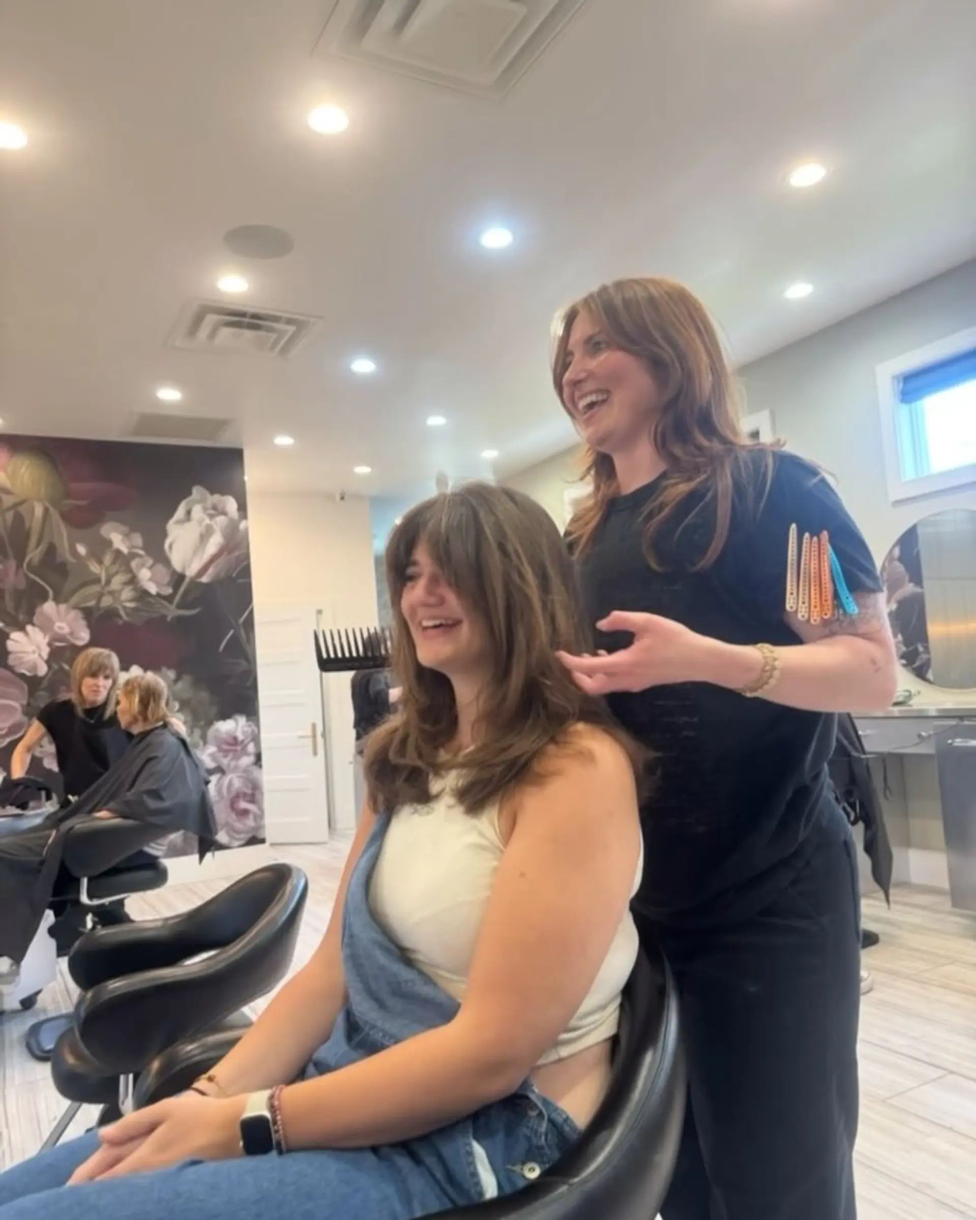 Medium-length layered haircut with face-framing curtain bangs styled in a soft, voluminous blowout. 1