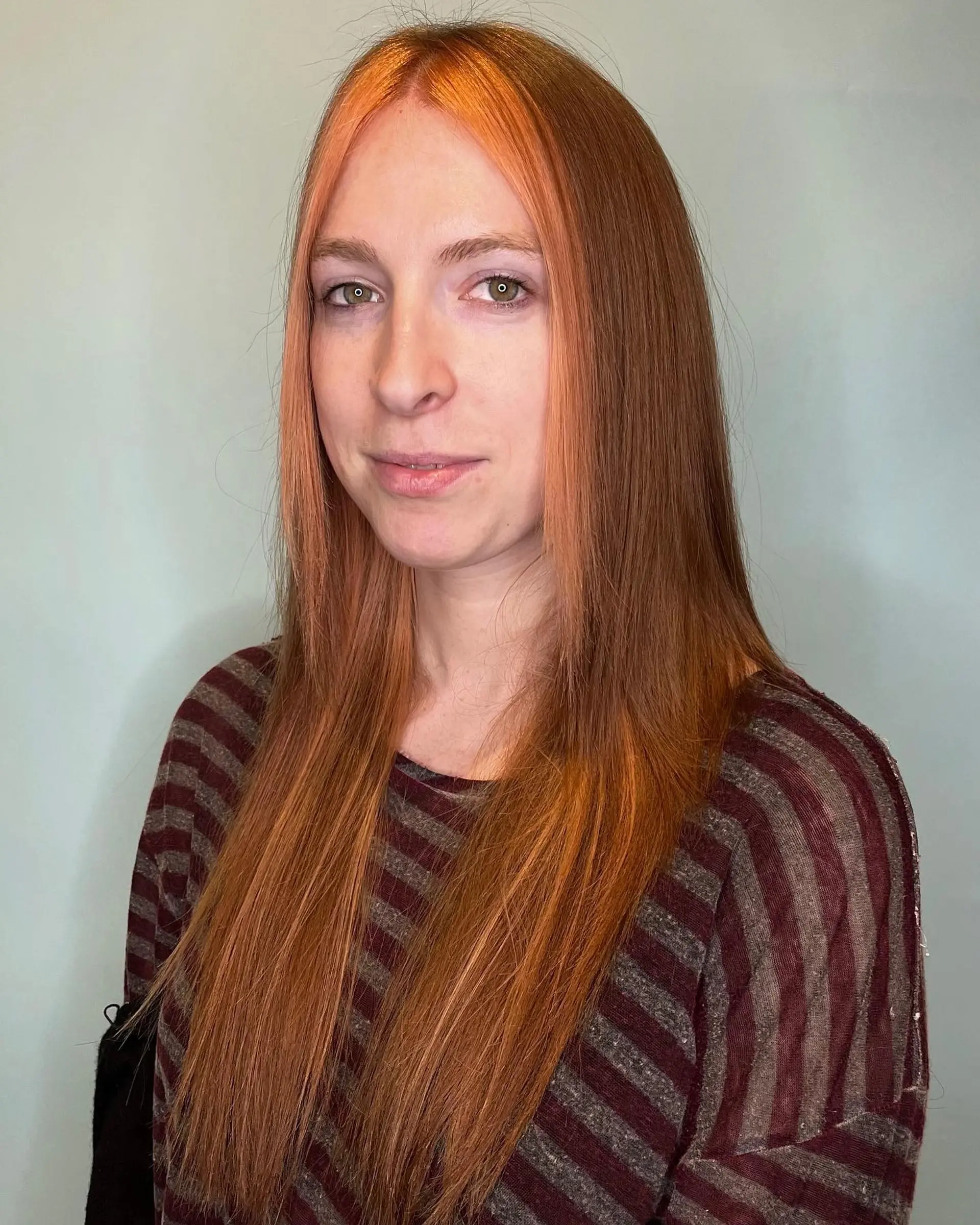 Long, straight hair with copper-red color and face-framing ginger money piece highlights. 2