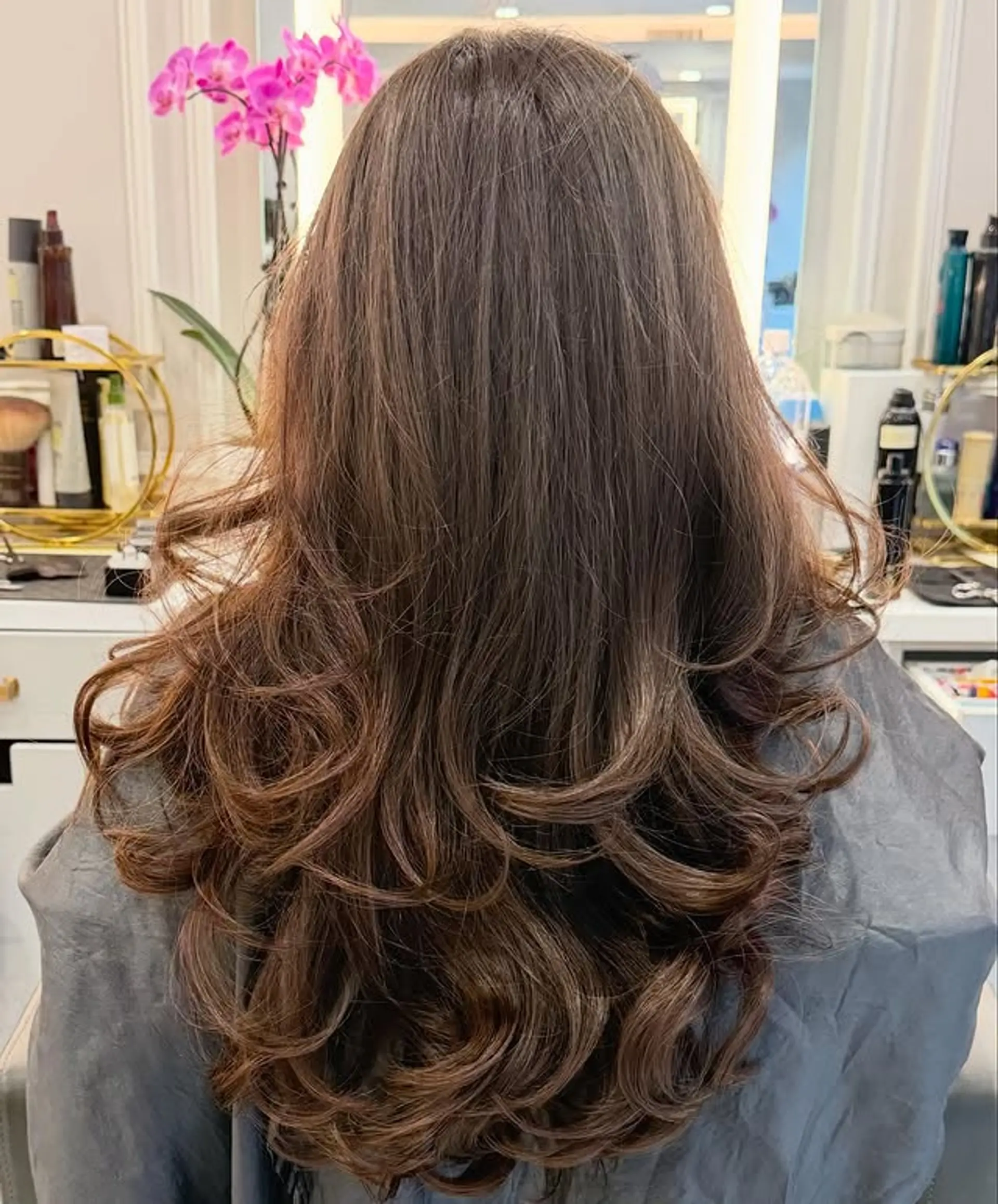 A layered haircut with long, wavy hair designed to create volume and movement. 1