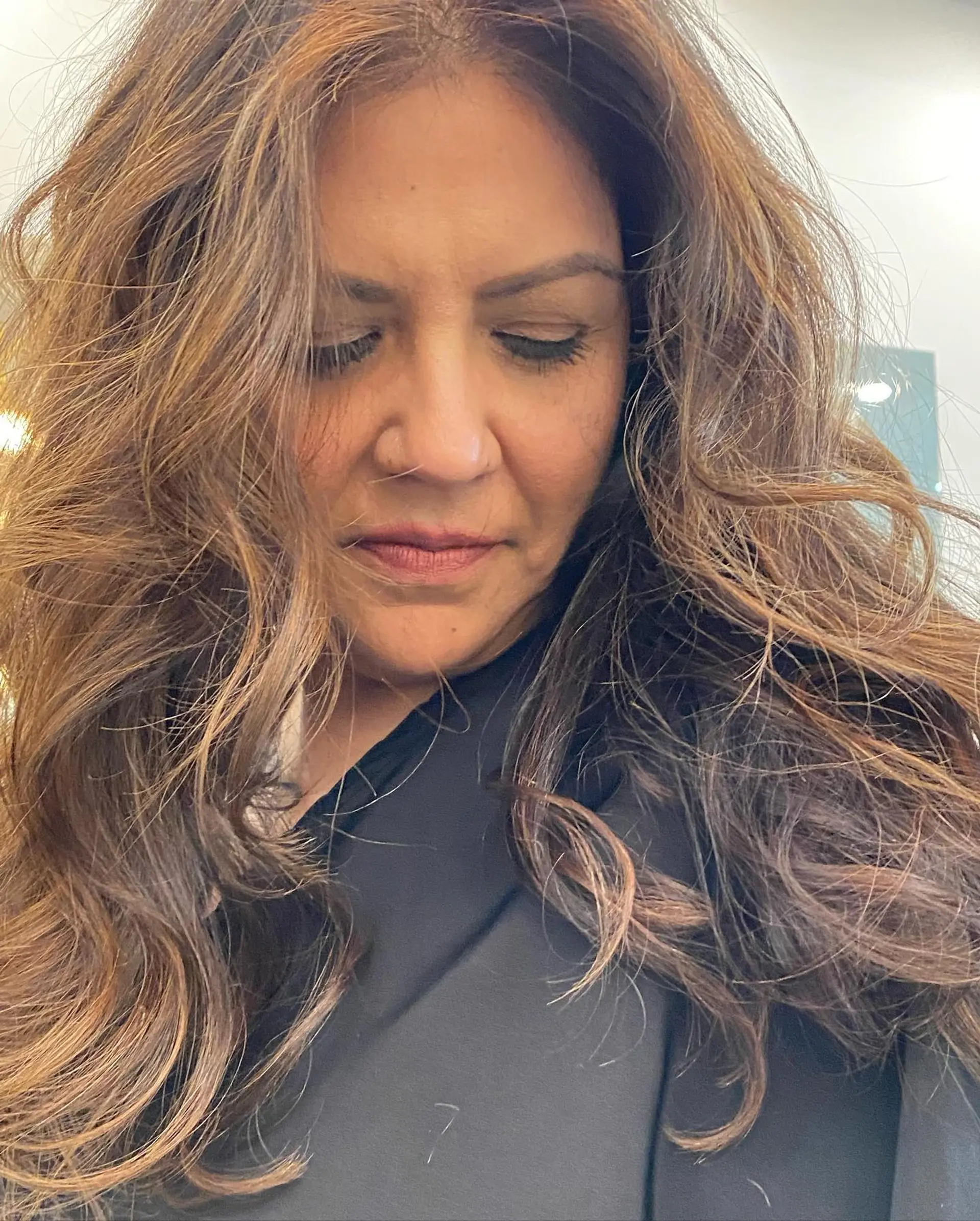 Long, dimensional warm brown hair cut in full layers and styled with tousled, voluminous waves. 1