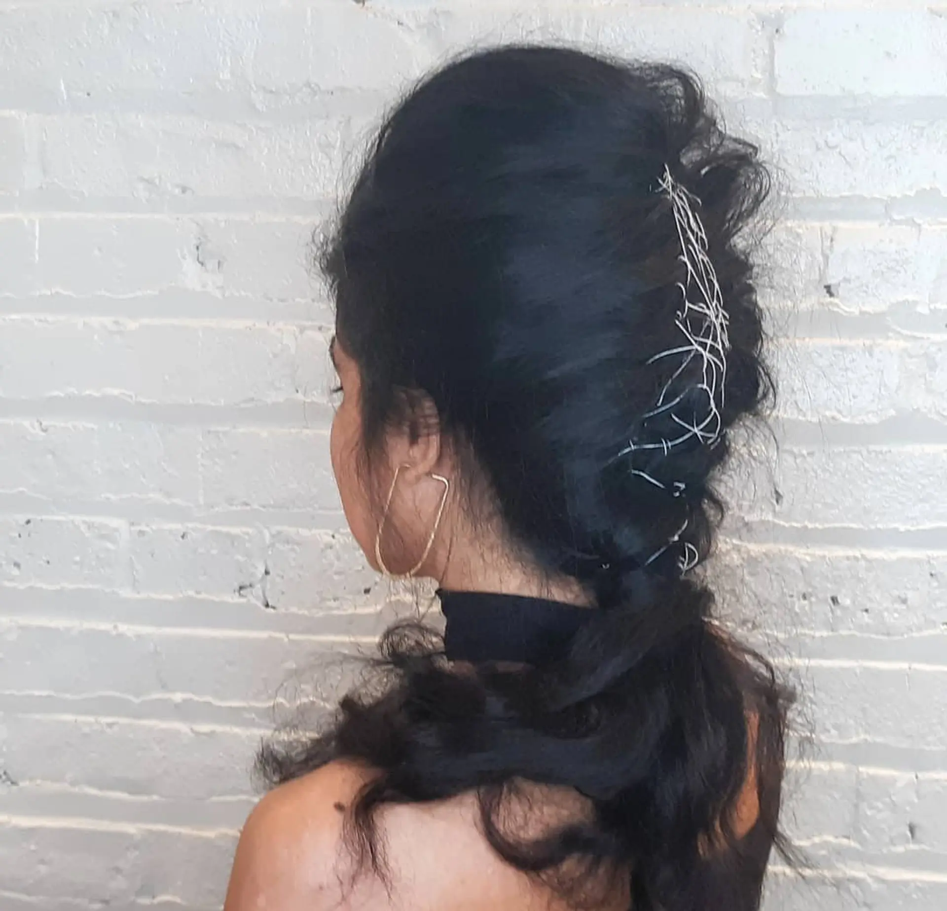 A long, wavy hair styled into a braided ponytail updo with decorative accents. 1