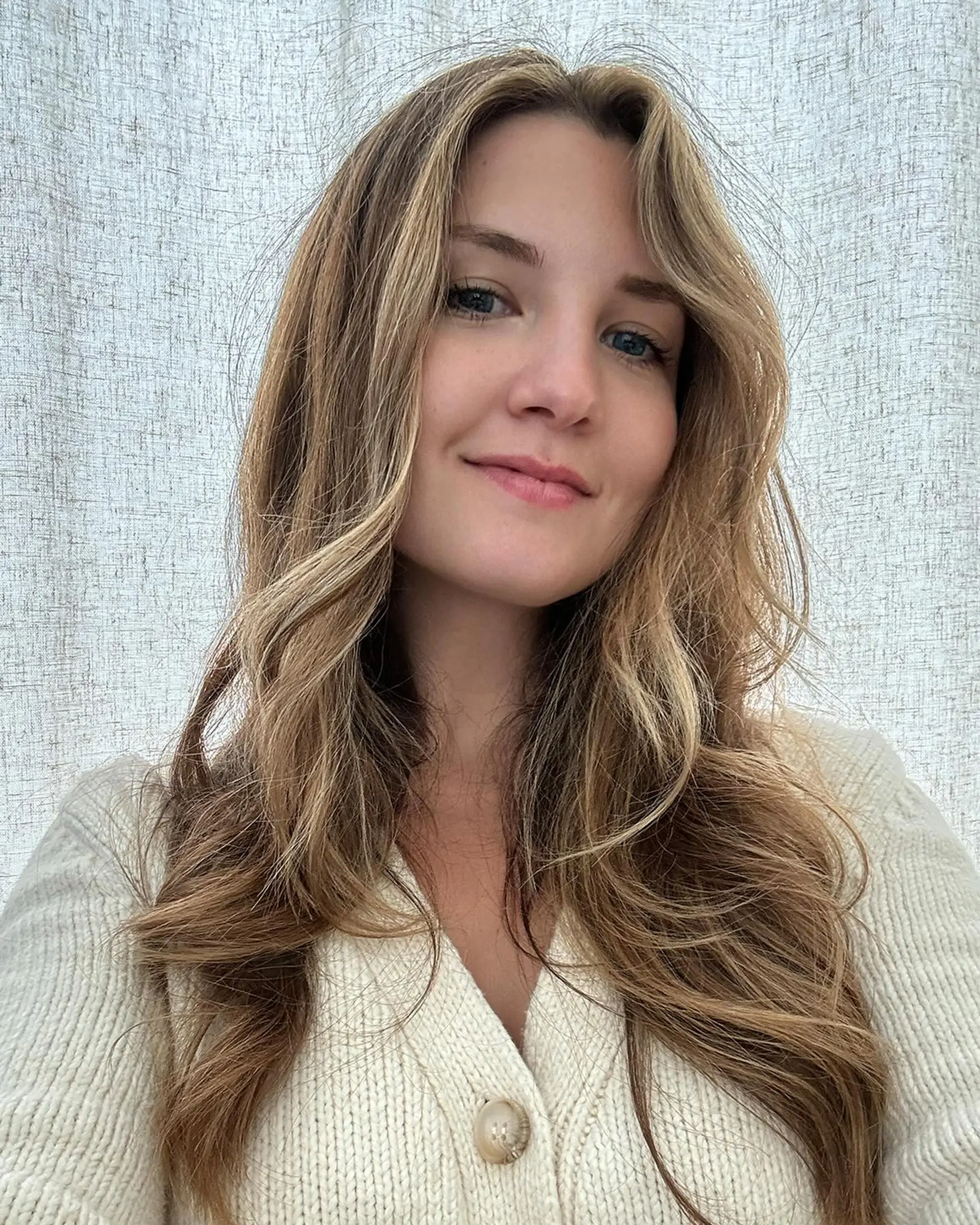 Long hair styled in soft, loose waves with subtle golden blonde highlights around the face. 1