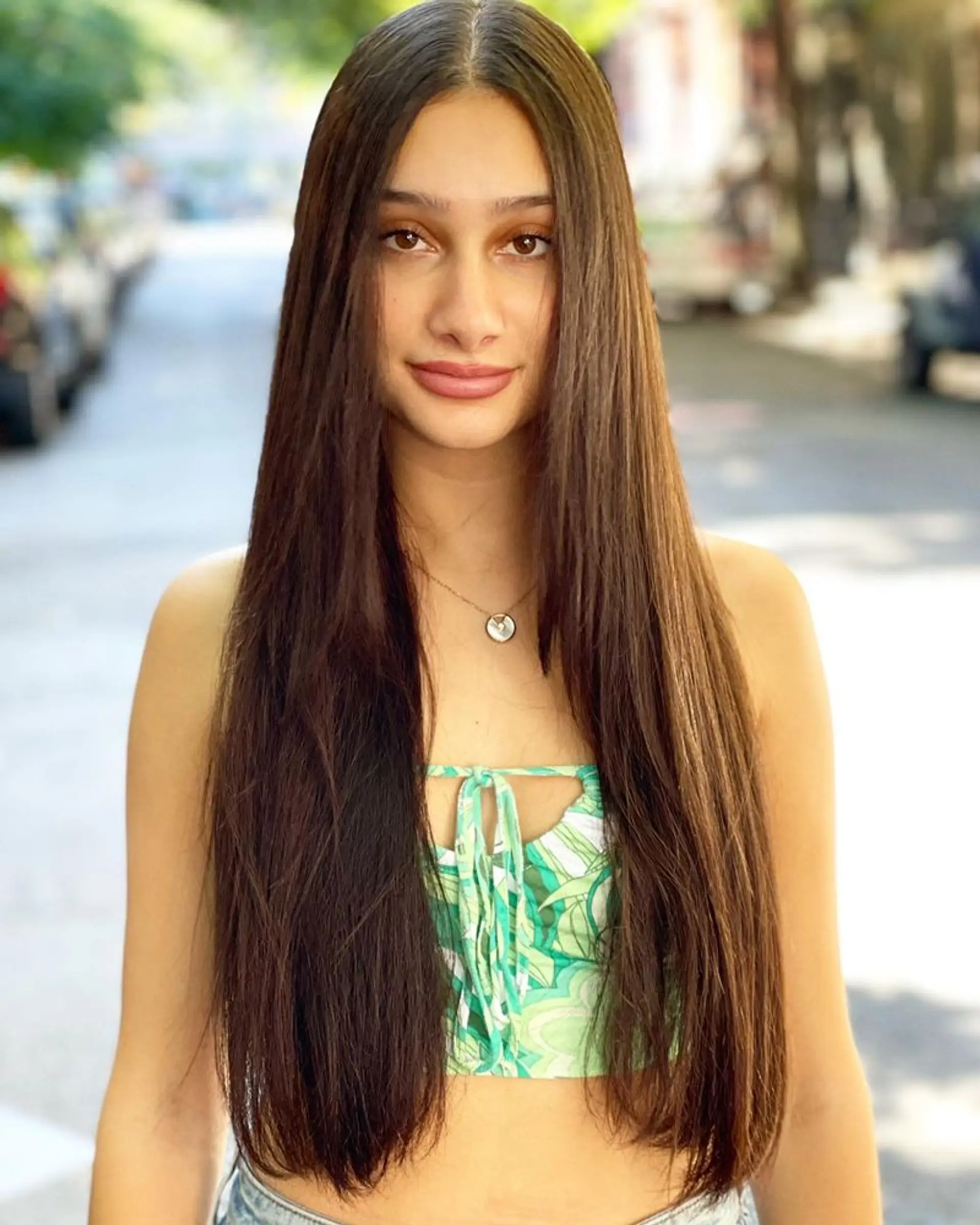 Very long, straight brunette hair, parted in the center for a sleek and polished look. 1