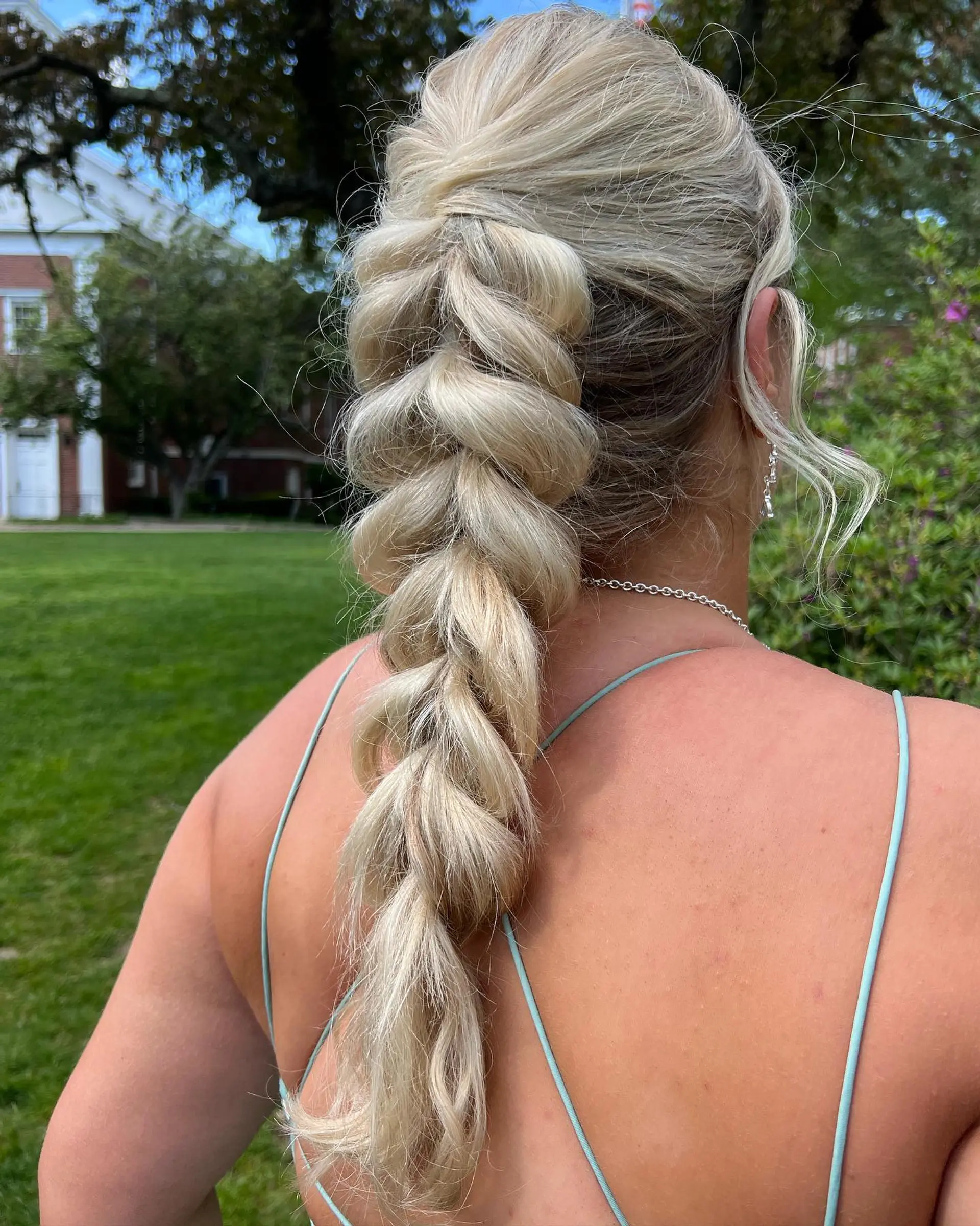 A thick, voluminous braided ponytail styled with soft, expanded pull-through sections for a formal, bohemian look. 1