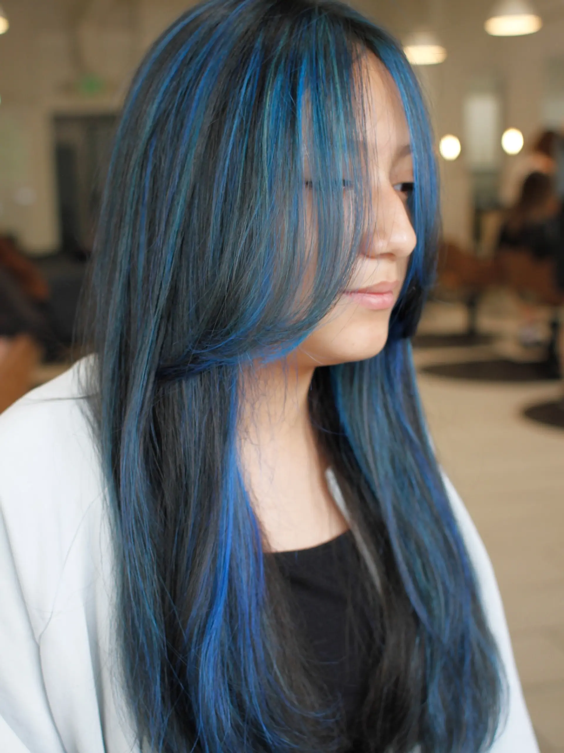 Long dark hair styled straight with vibrant electric blue highlights throughout and layered, face-framing fringe. 1