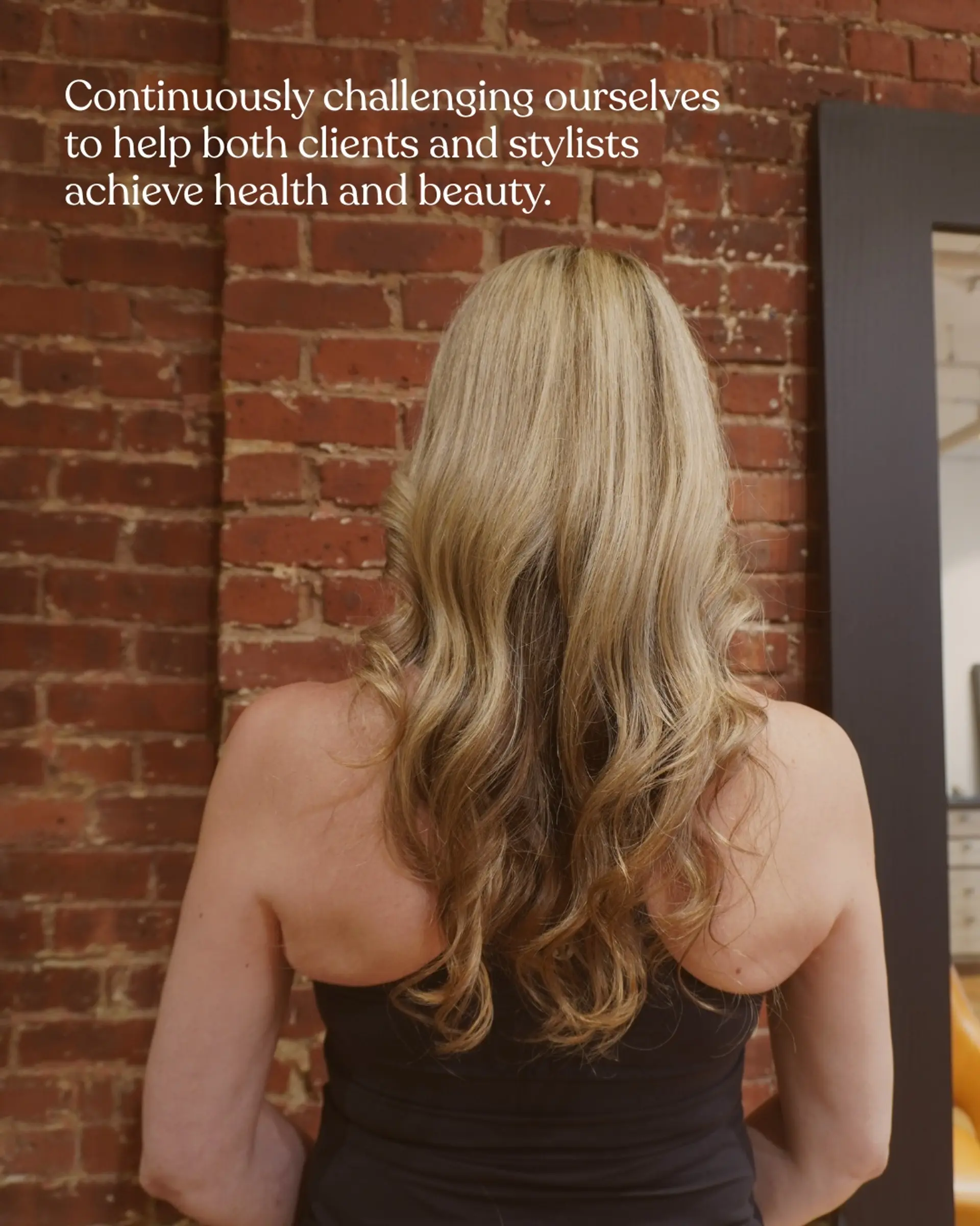 Long warm blonde hair styled into soft, natural waves cascading down the back. 1