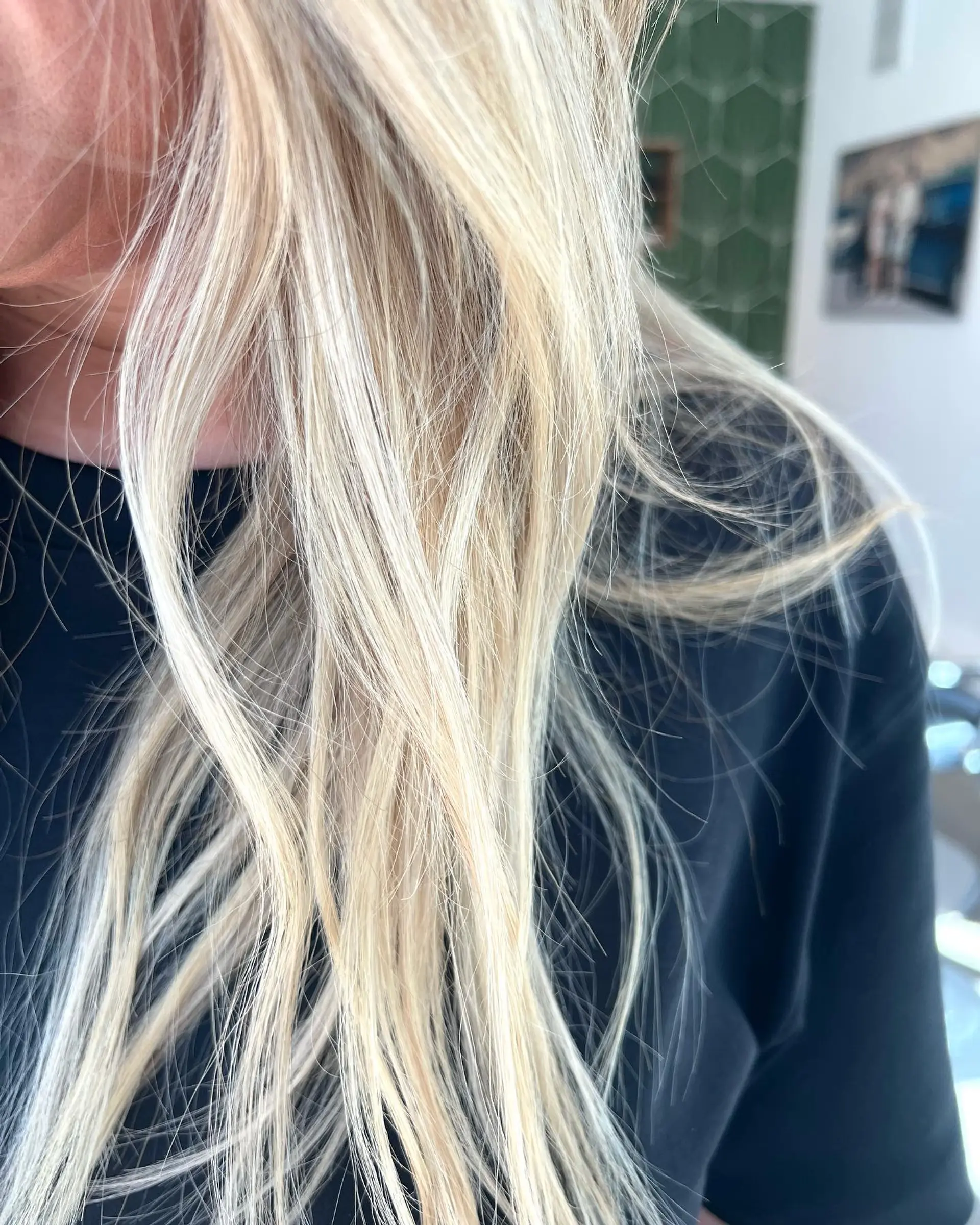 A close-up shot of bright, multi-dimensional blonde hair with fine, textured strands draped over the shoulder. 1