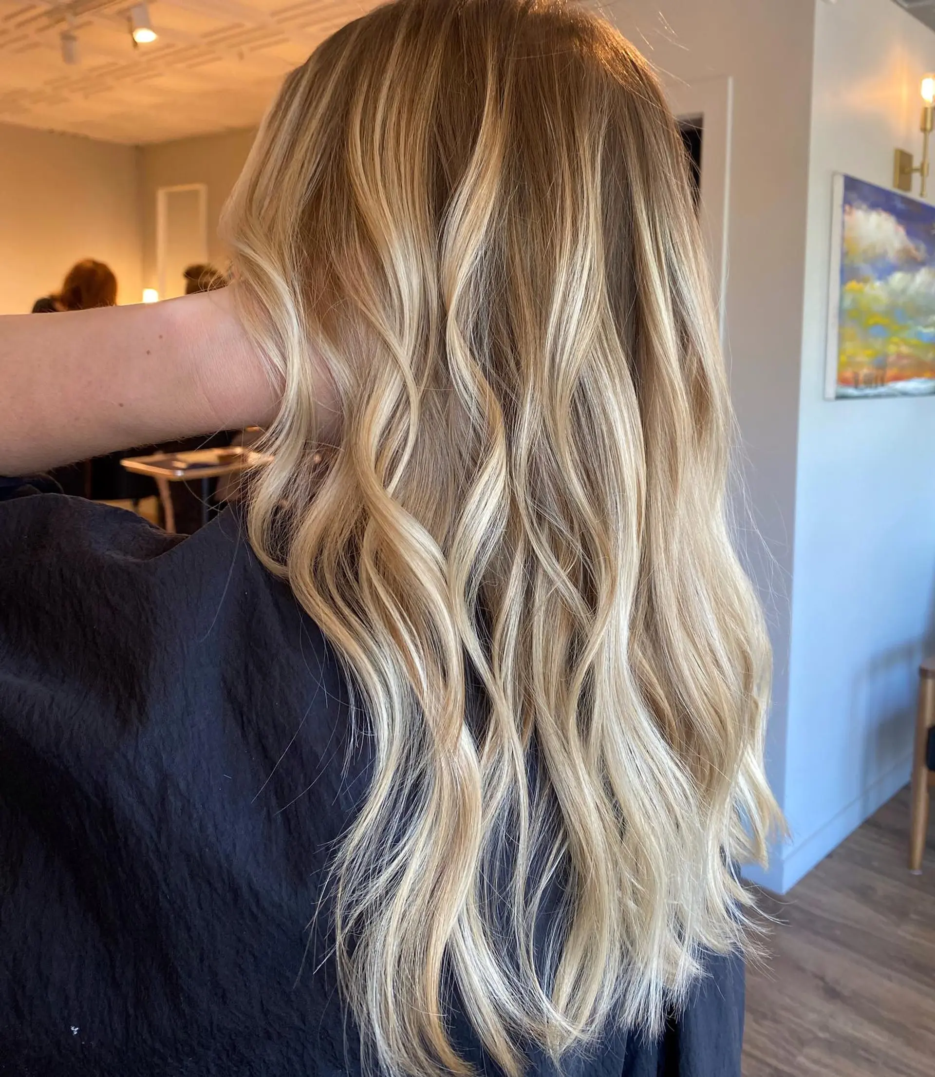 Long, dimensional blonde balayage styled with soft, cascading waves. 1