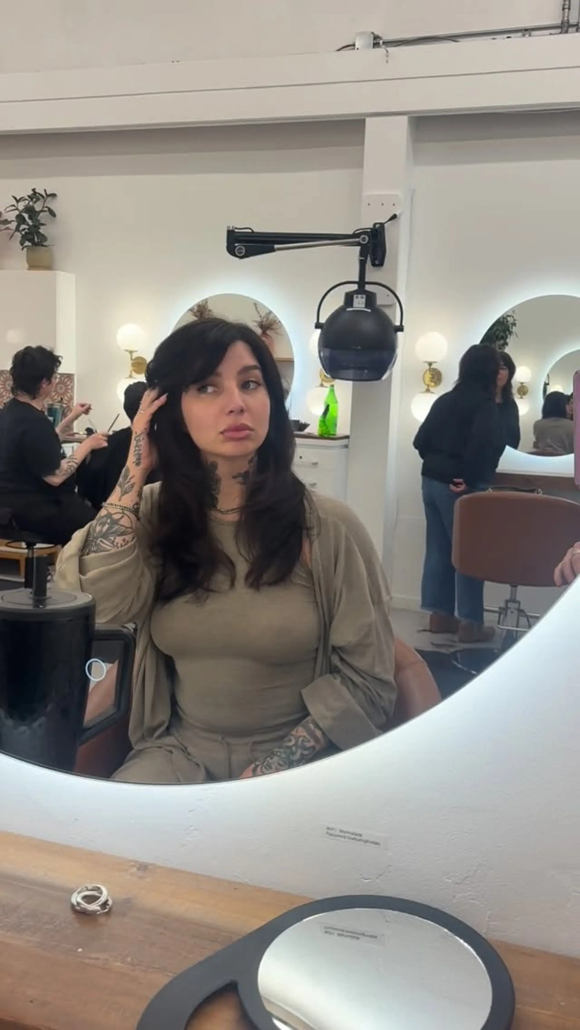 Medium-length dark brunette hair cut with soft, face-framing layers and side-swept curtain bangs with natural texture. 1
