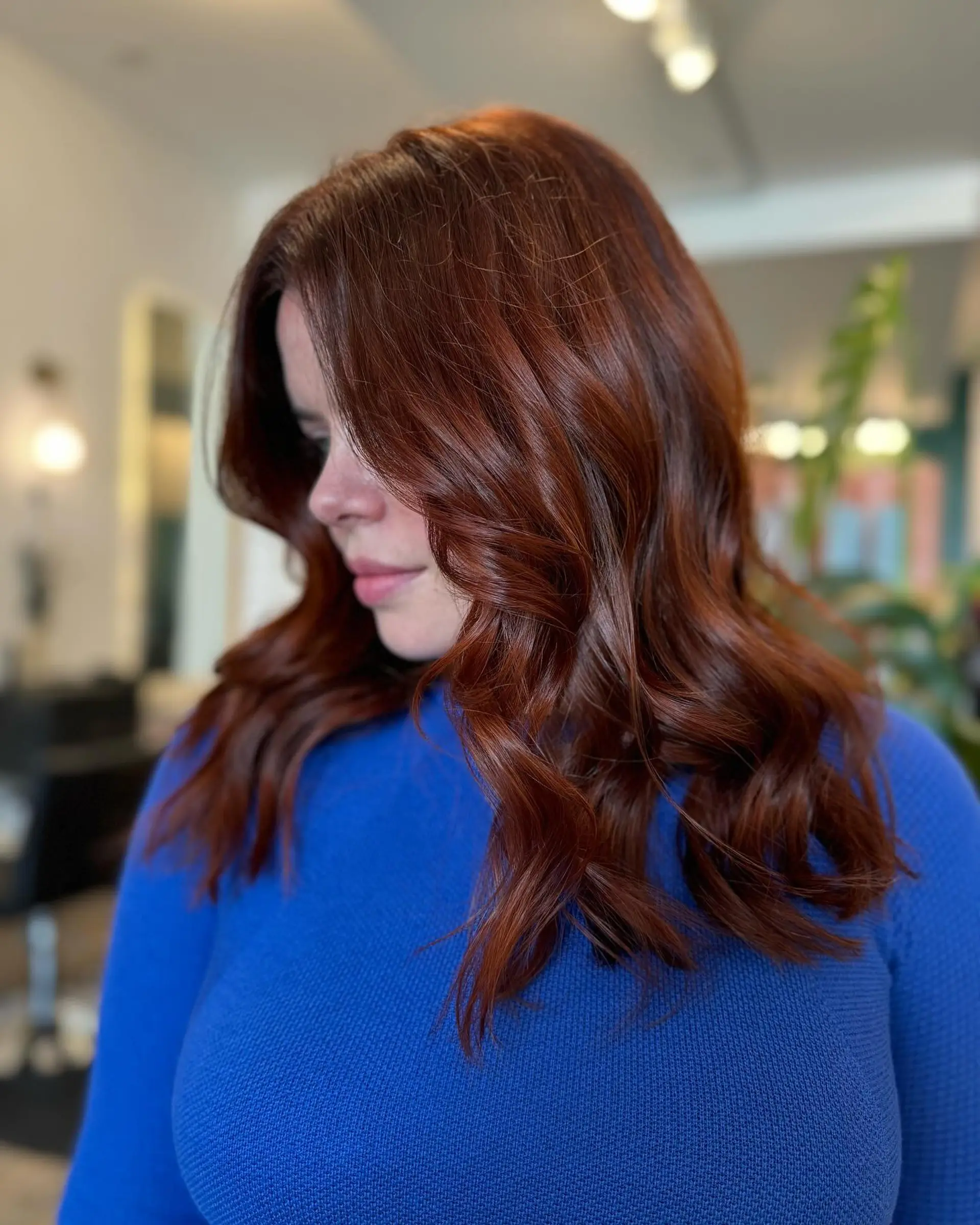 A vibrant, glossy auburn all-over color styled into soft, flowing waves. 1