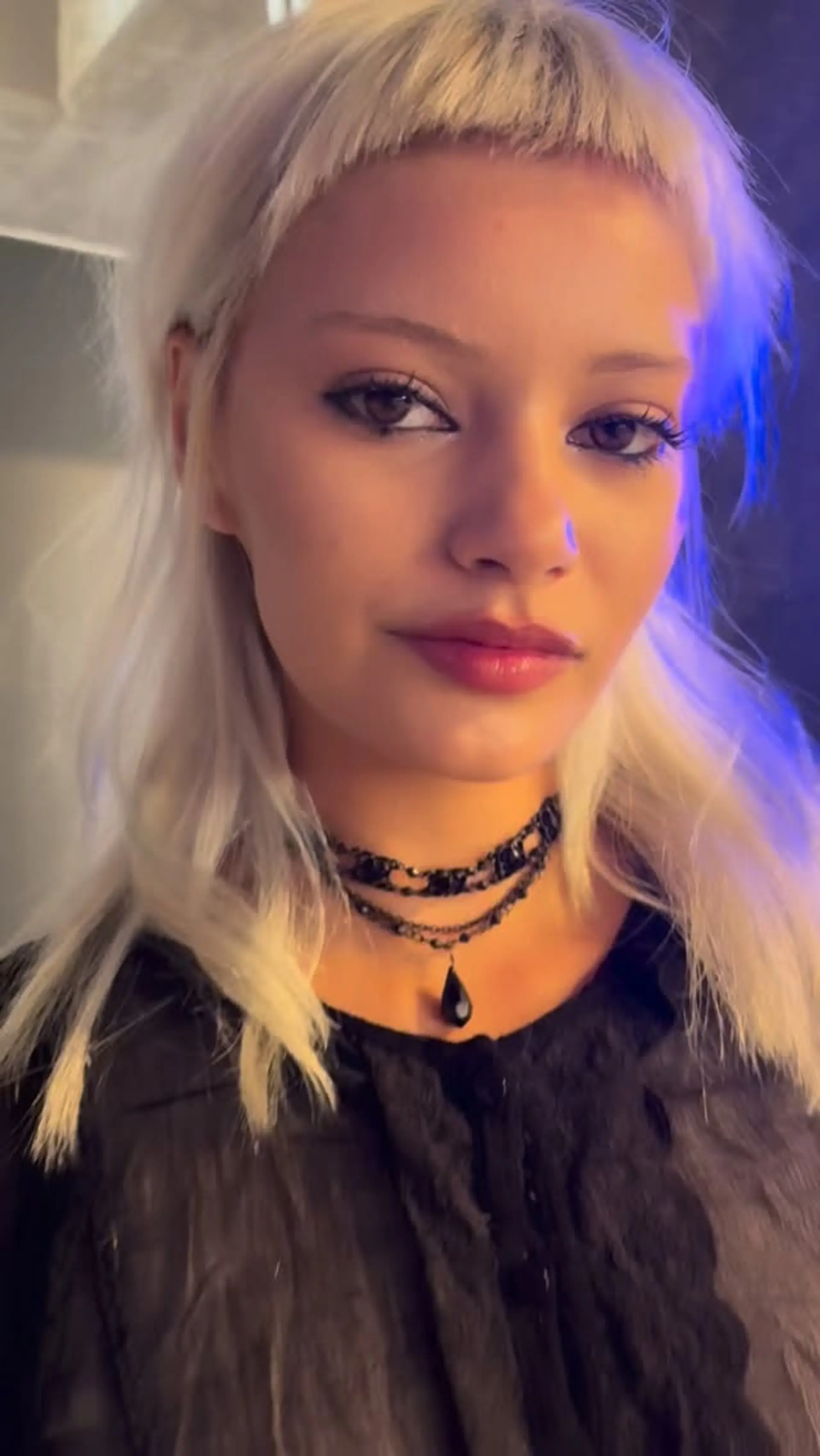 A textured platinum blonde cut featuring wispy micro bangs and feathered, shoulder-length layers. 1