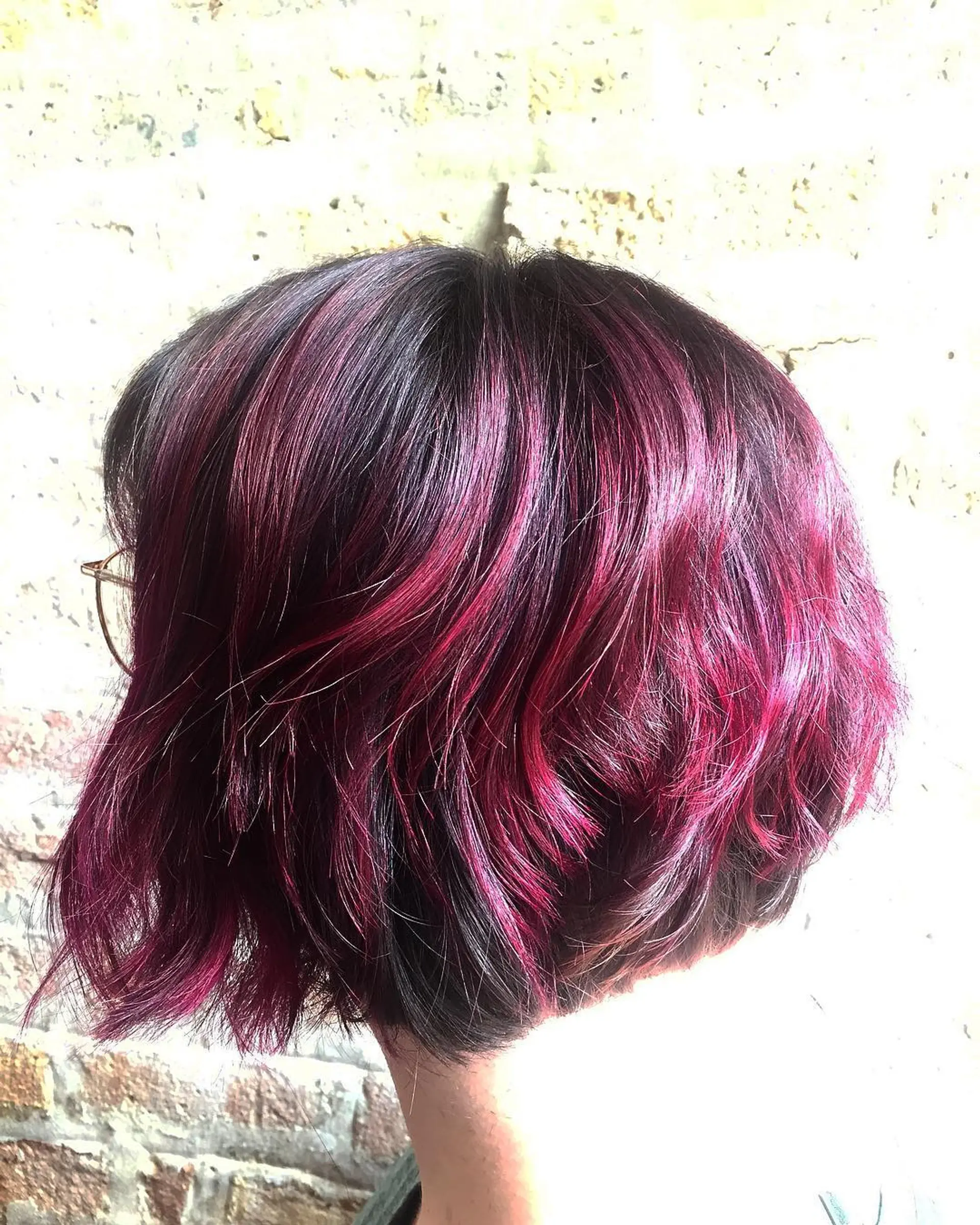 A short, wavy bob with textured layers and bold berry red highlights. 1