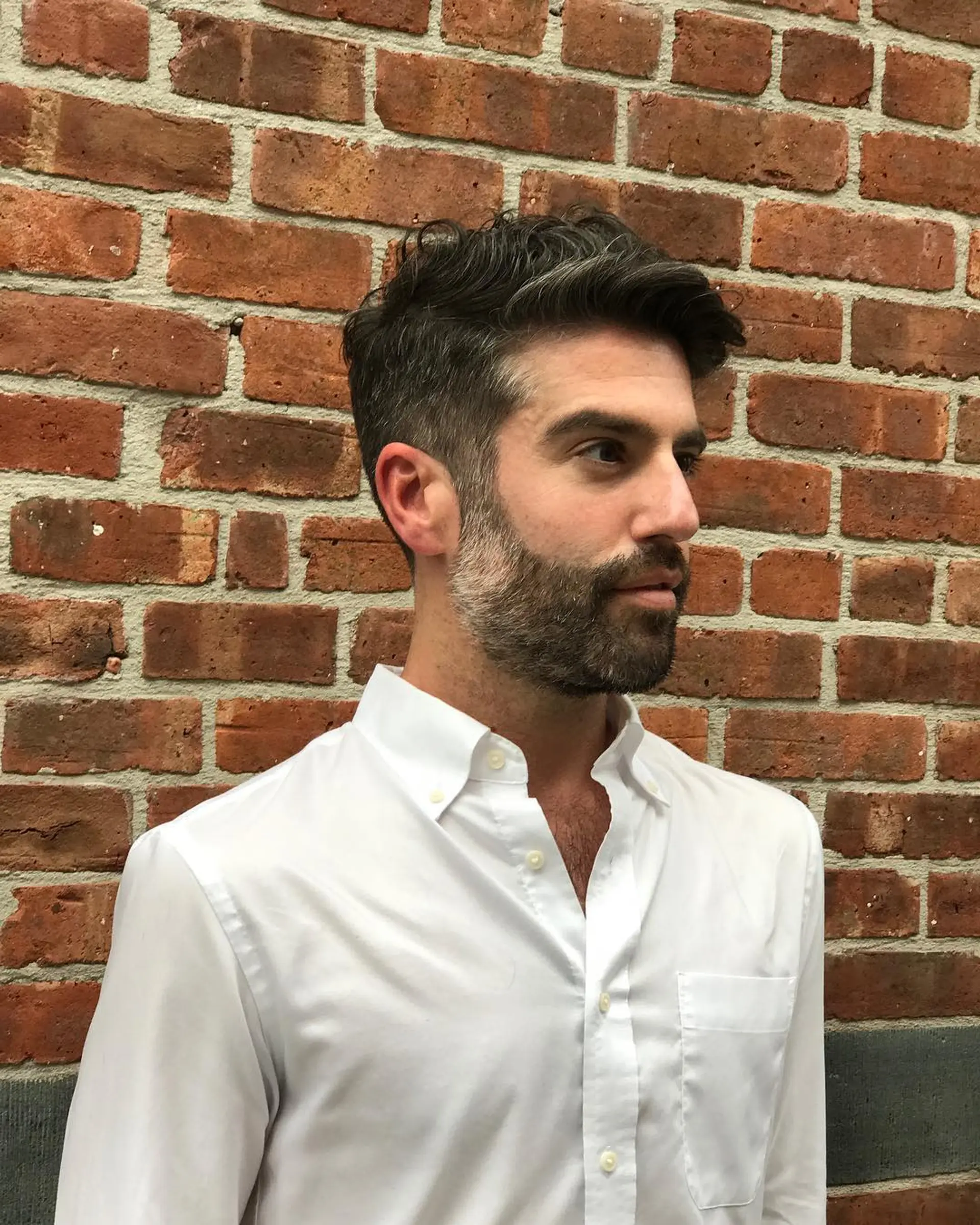 A clean clipper cut with tapered sides and a textured, naturally wavy top styled neatly back. 1