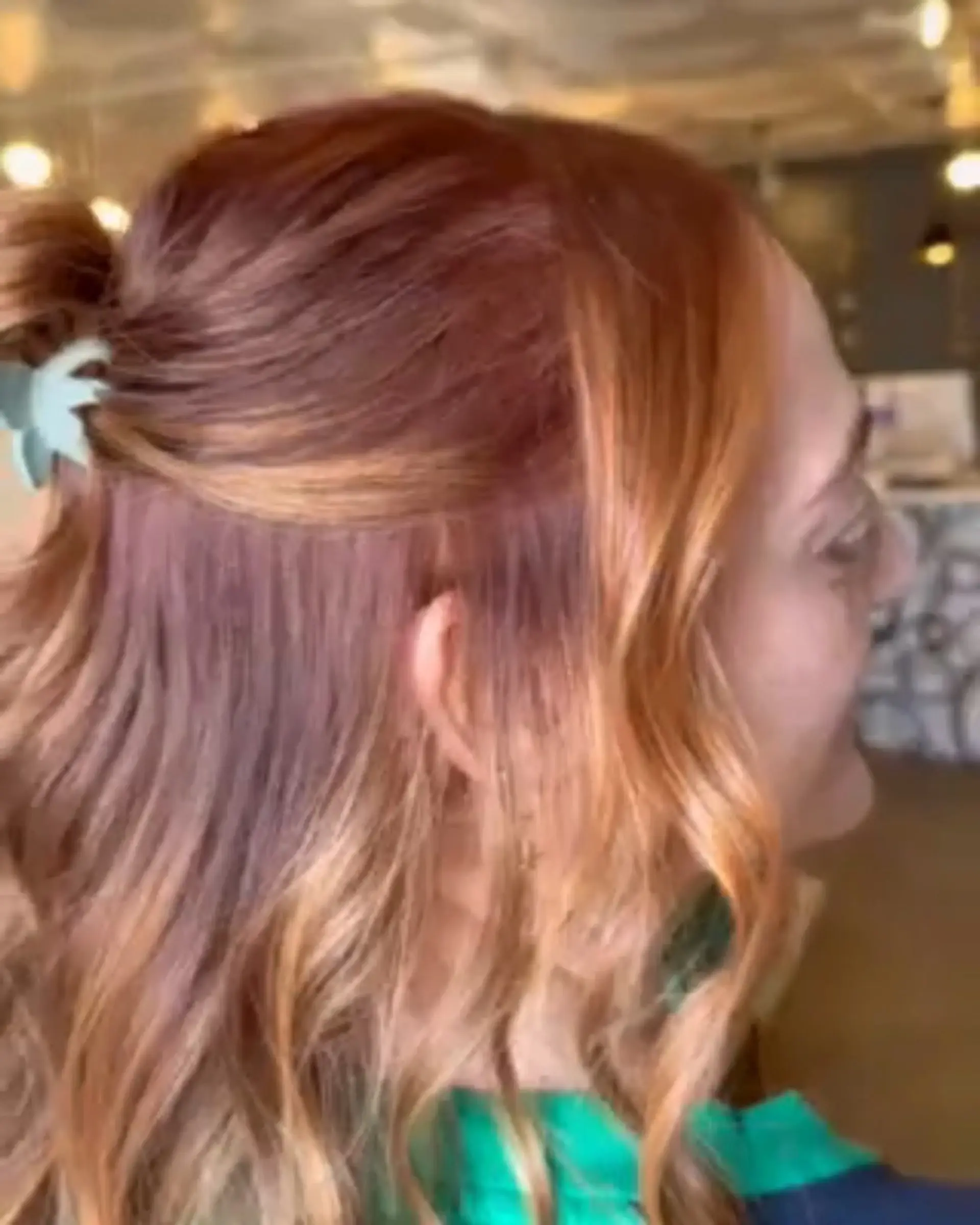 Dimensional warm copper and caramel tones styled into soft waves with an effortless half-up claw clip accent. 1