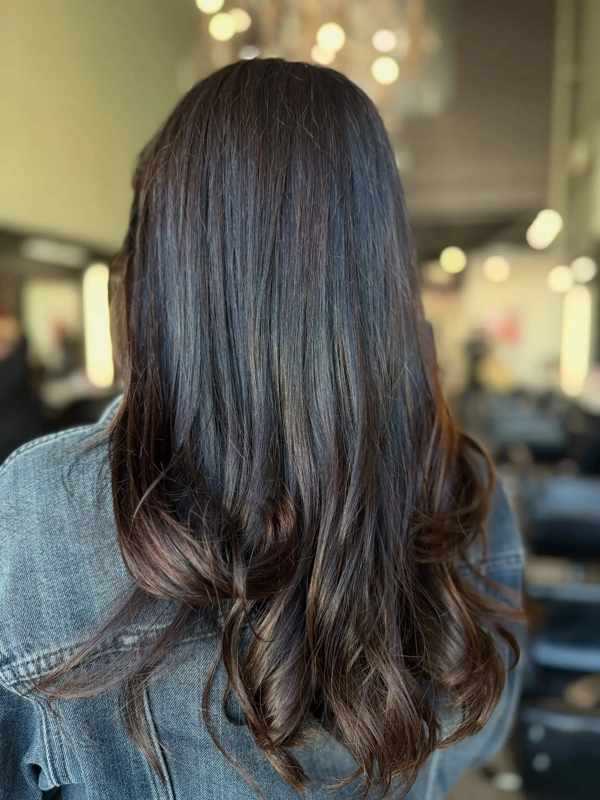 Long, glossy dark brunette hair smoothly blown out with soft, voluminous curls at the ends. 1