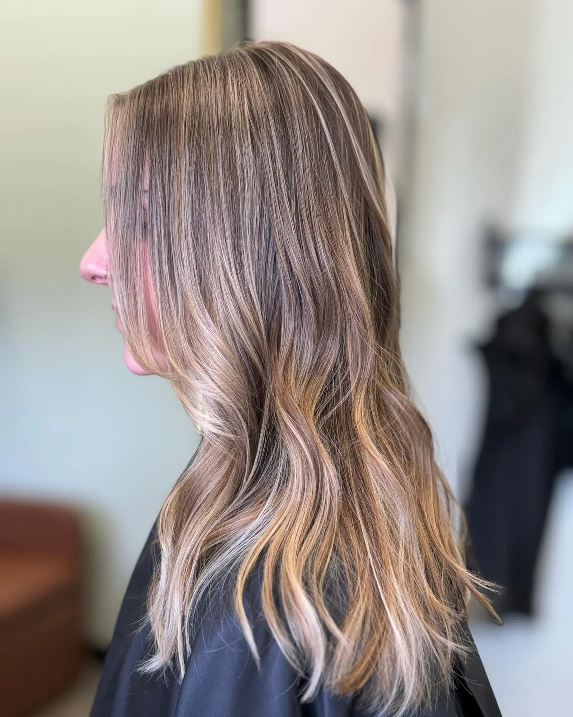 Long hair featuring a seamless dimensional blonde foilayage with fine ribbon highlights and soft, loose waves. 1