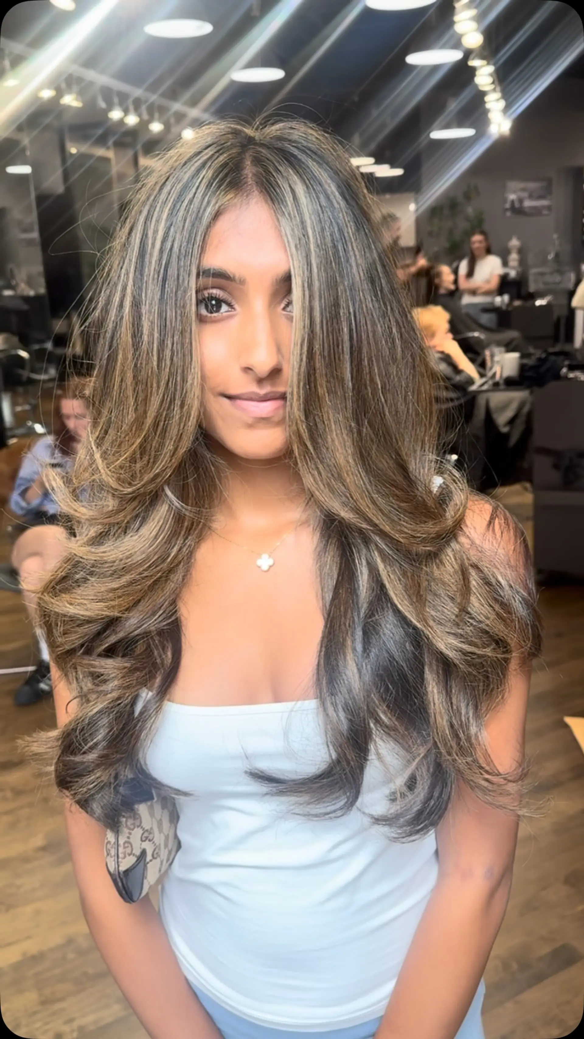 Long layered cut featuring finely blended dimensional highlights, styled into a voluminous blowout with soft flipped ends and face-framing pieces. 1