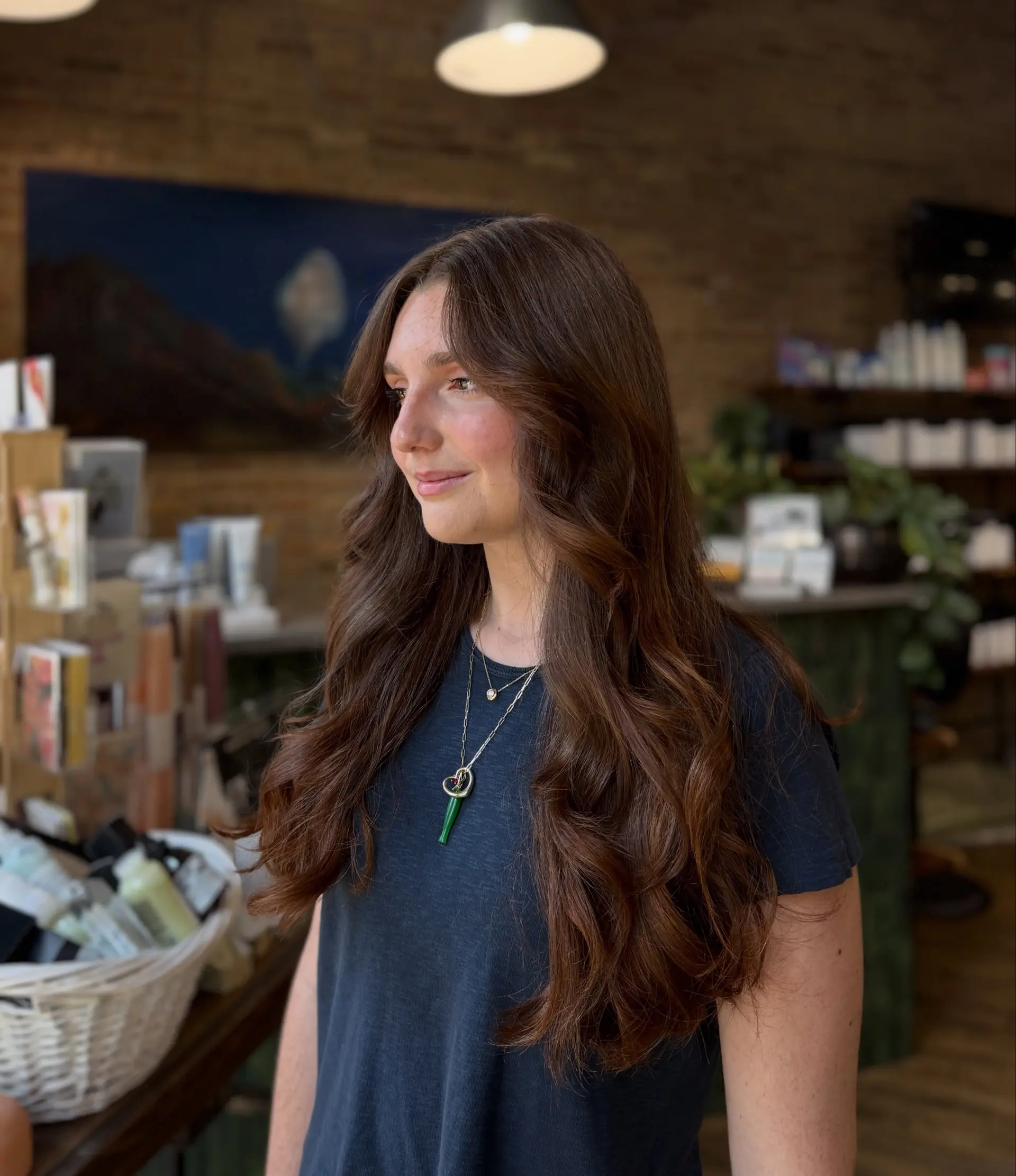 Long chocolate brunette hair with face-framing curtain bangs and soft, voluminous waves. 1