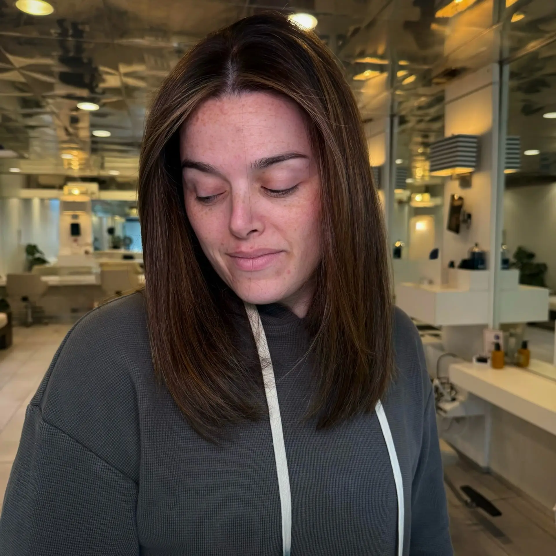 Collarbone-length straight lob featuring a rich brown base with delicate, subtle balayage and soft face-framing highlights. 1