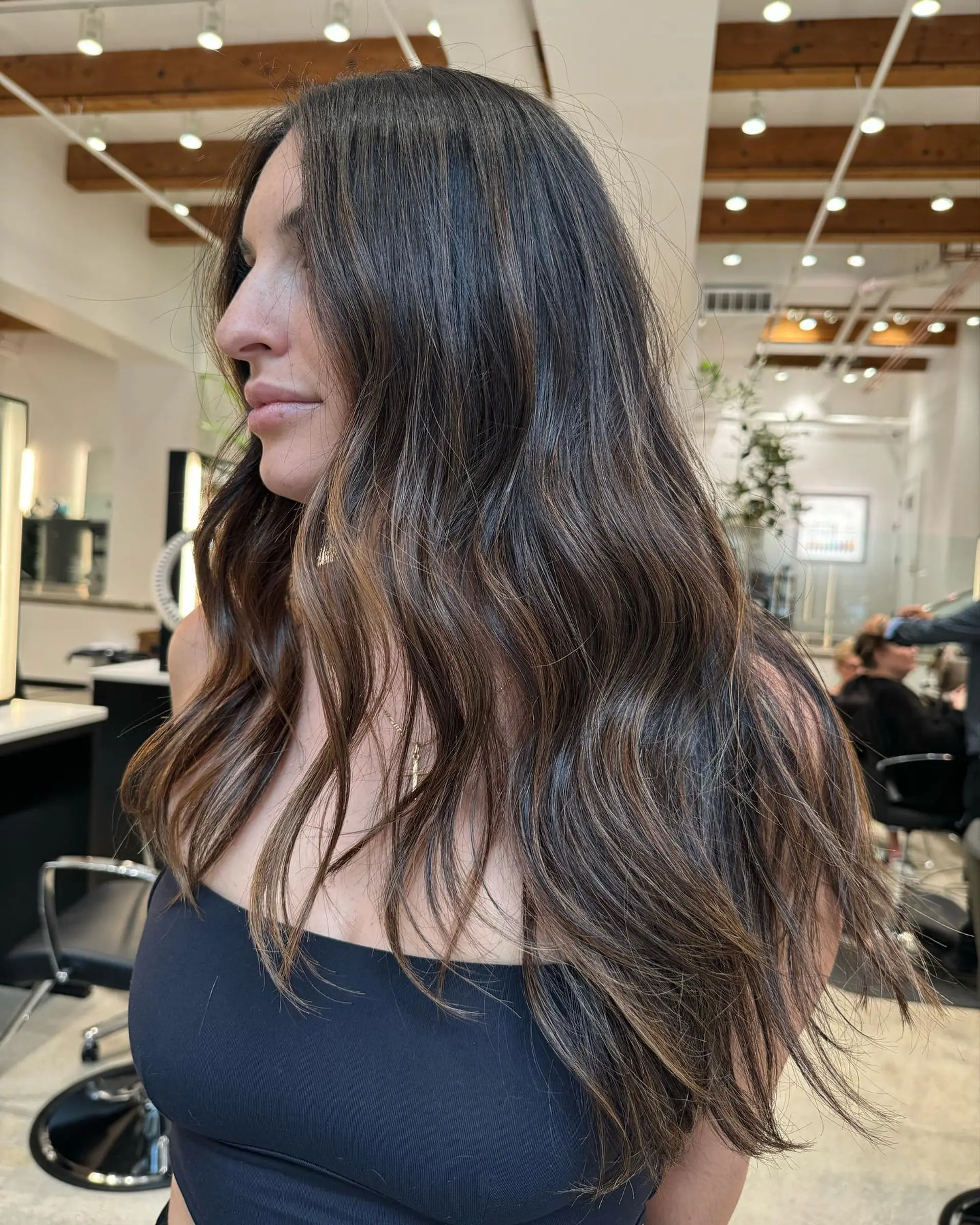 Long brunette hair with caramel balayage styled into soft, beachy waves. 1