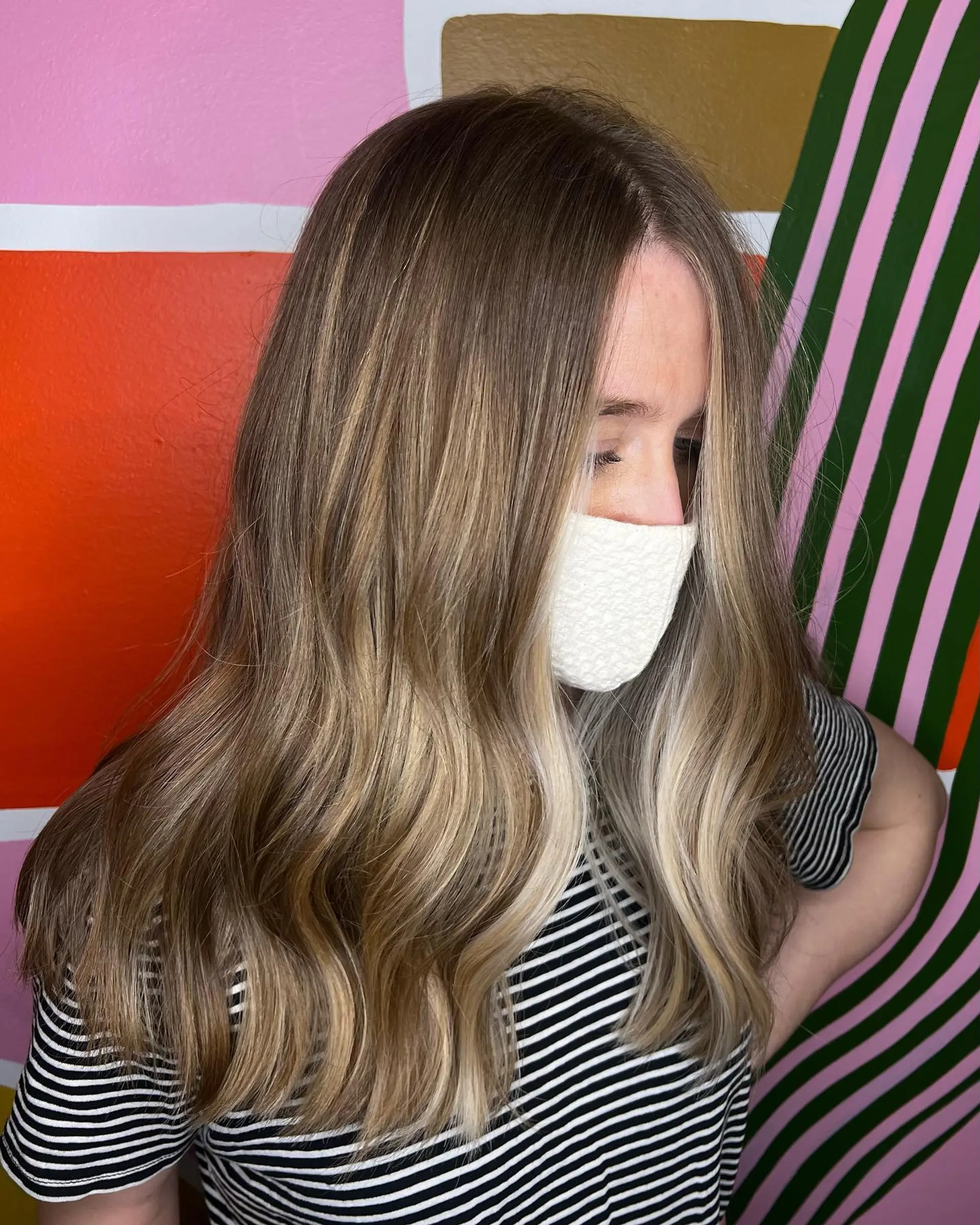 Long hair featuring dimensional blonde balayage with a striking bright money piece, styled in soft waves. 1