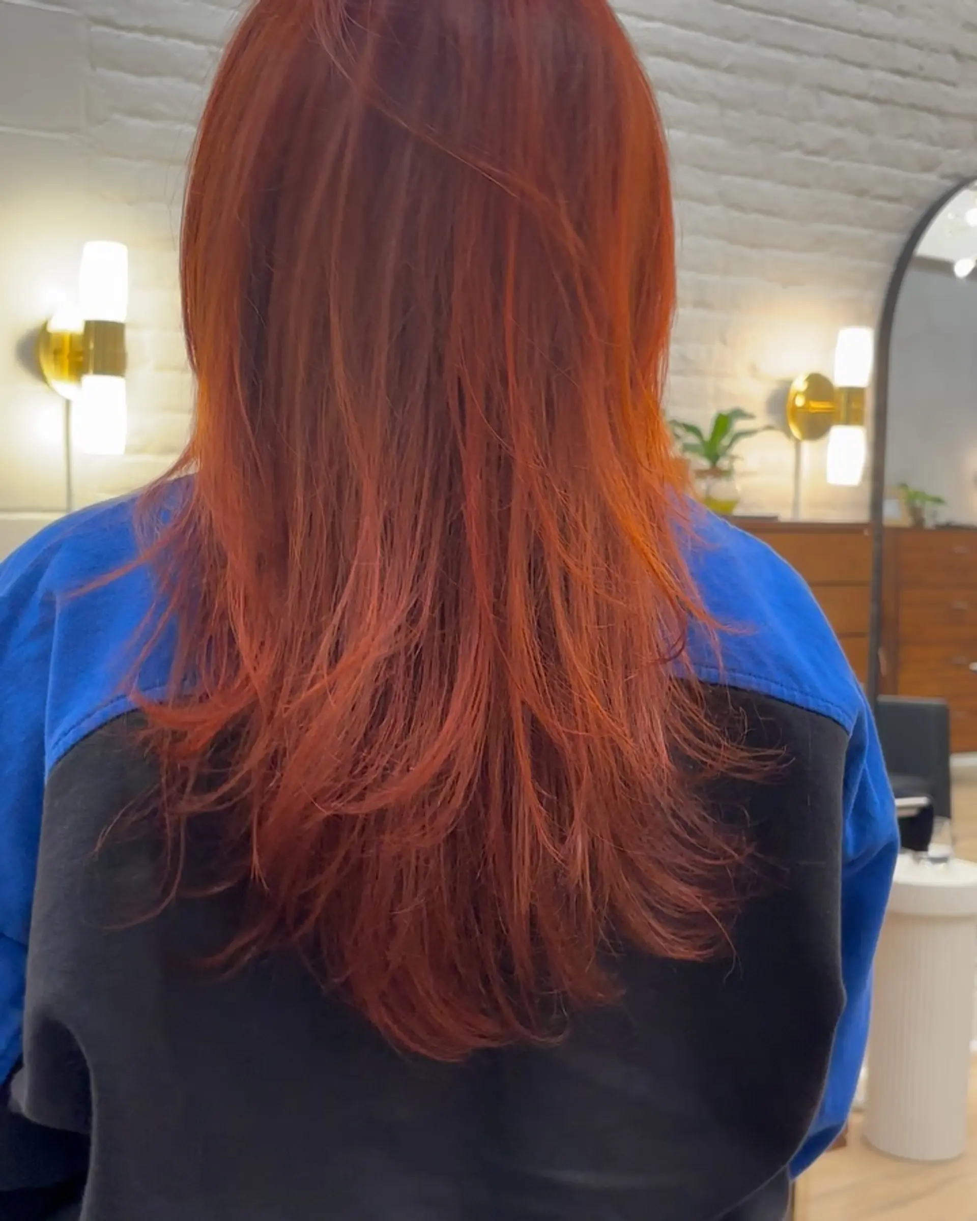 Vibrant copper-red long hair styled with soft, cascading feather layers and a smooth finish. 1