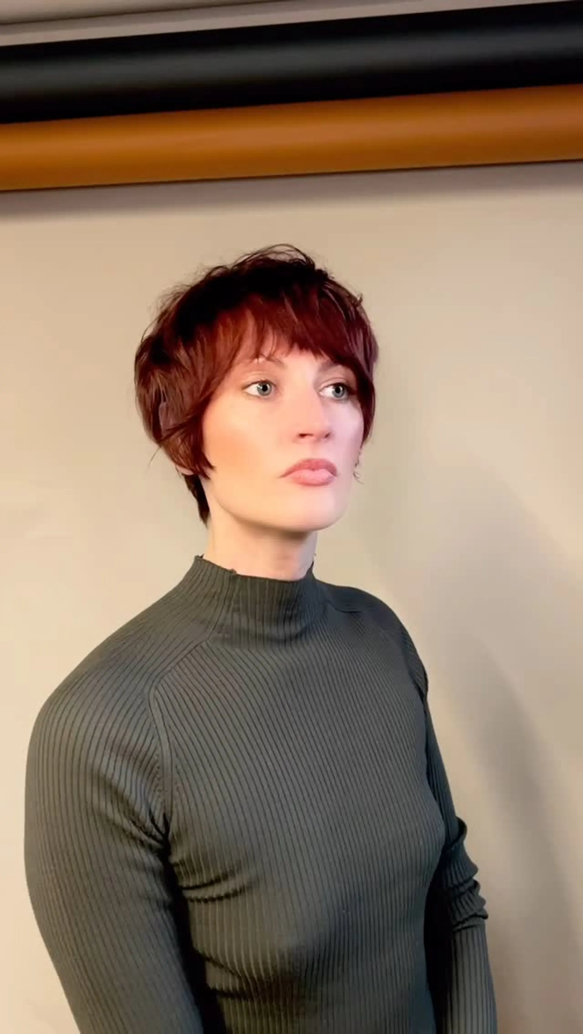 A razored bixie cut with textured layering, piecey fringe, and soft face-framing pieces in a warm auburn shade. 1