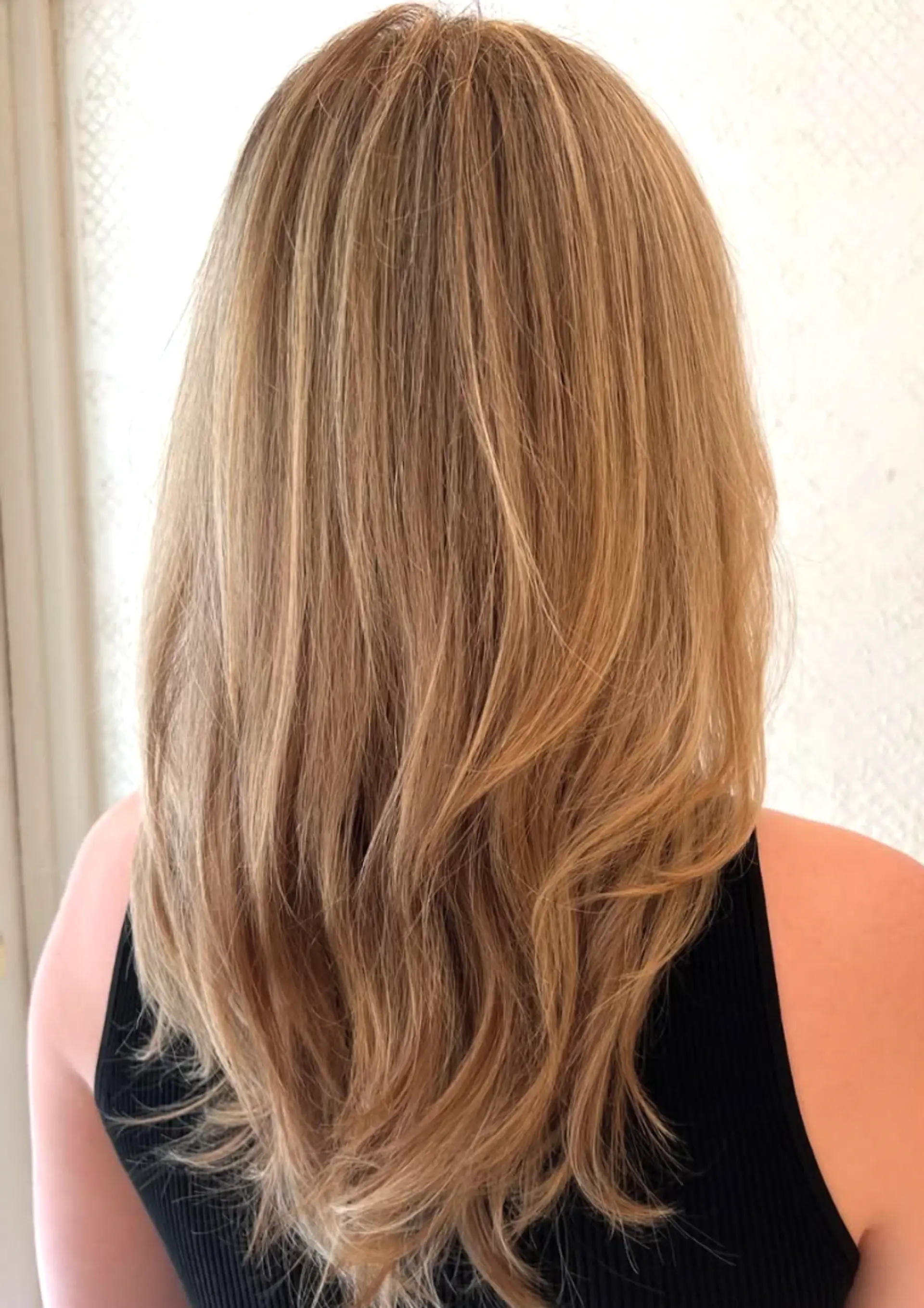 A long, wavy hairstyle with layered, natural waves in blonde and honey tones. 1