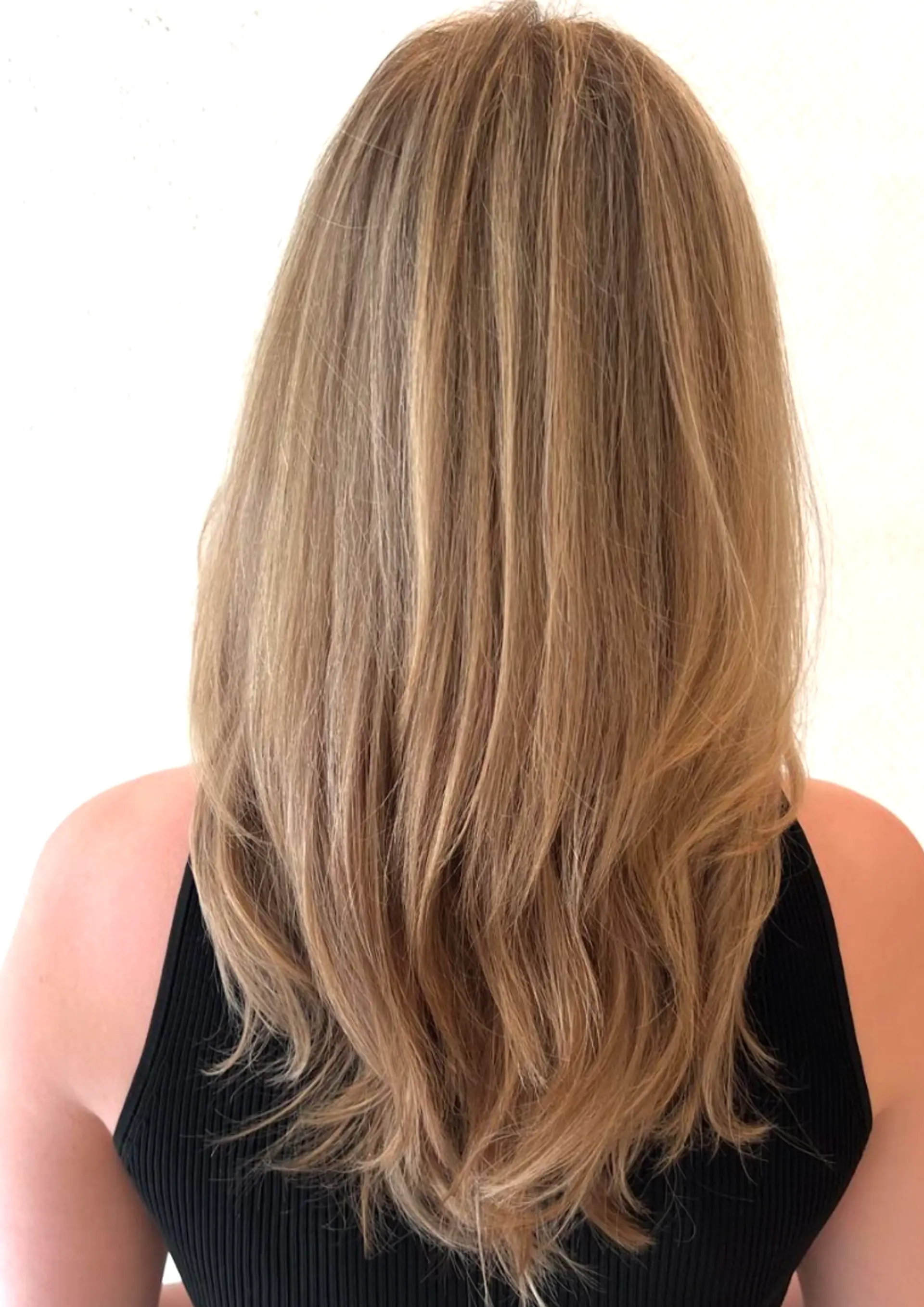 A long, wavy hairstyle with layered, natural waves in blonde and honey tones. 2