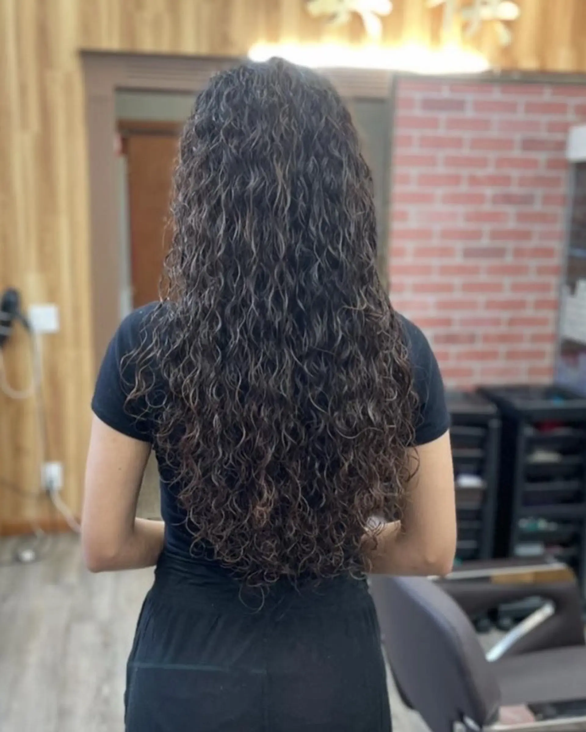 Very long, cascading spiral curls with defined texture and natural volume, falling past the mid-back in a gentle V-shape. 1
