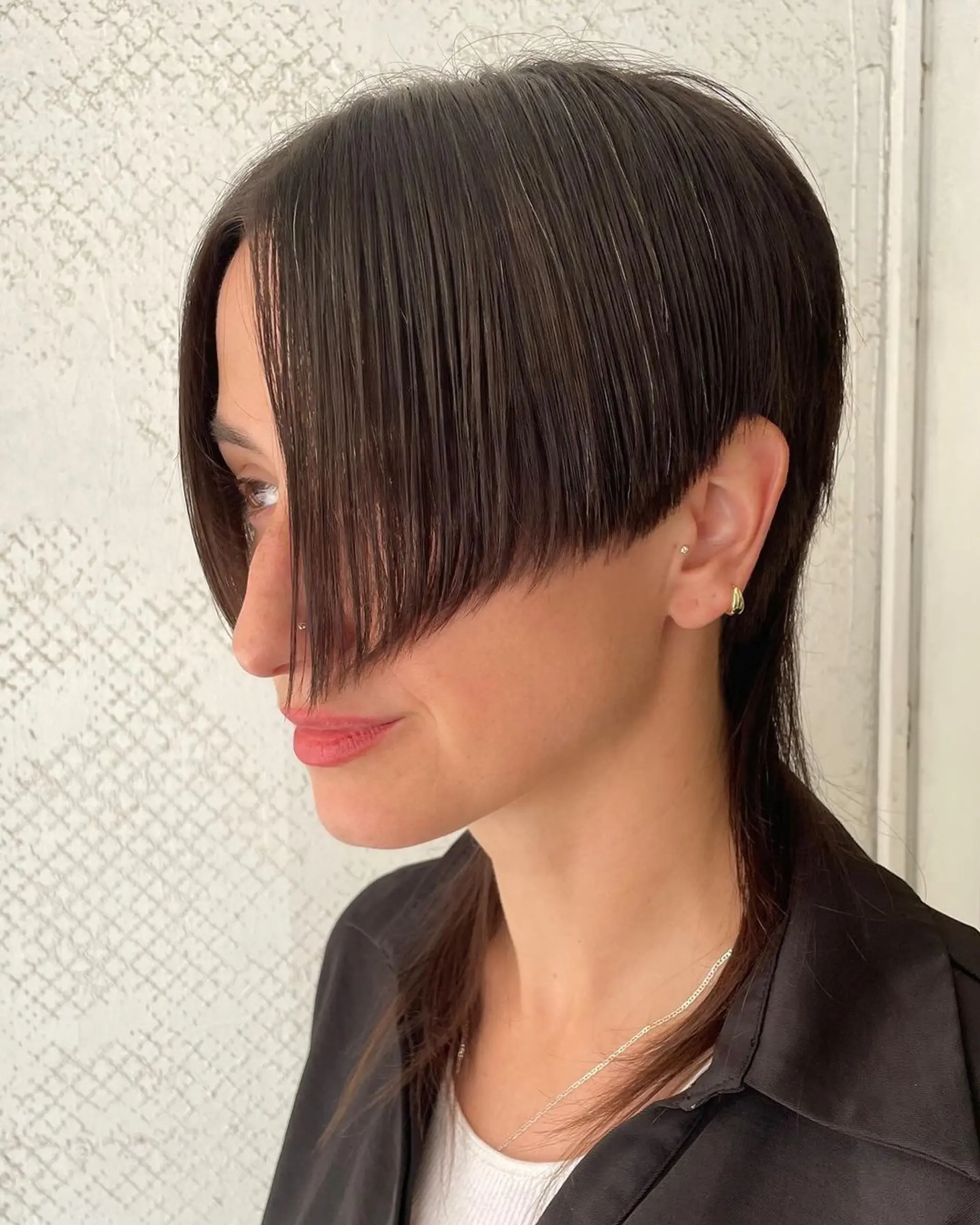 A sleek, asymmetrical layered bob with a deep side fringe, featuring neck-length dark brown straight hair. 1